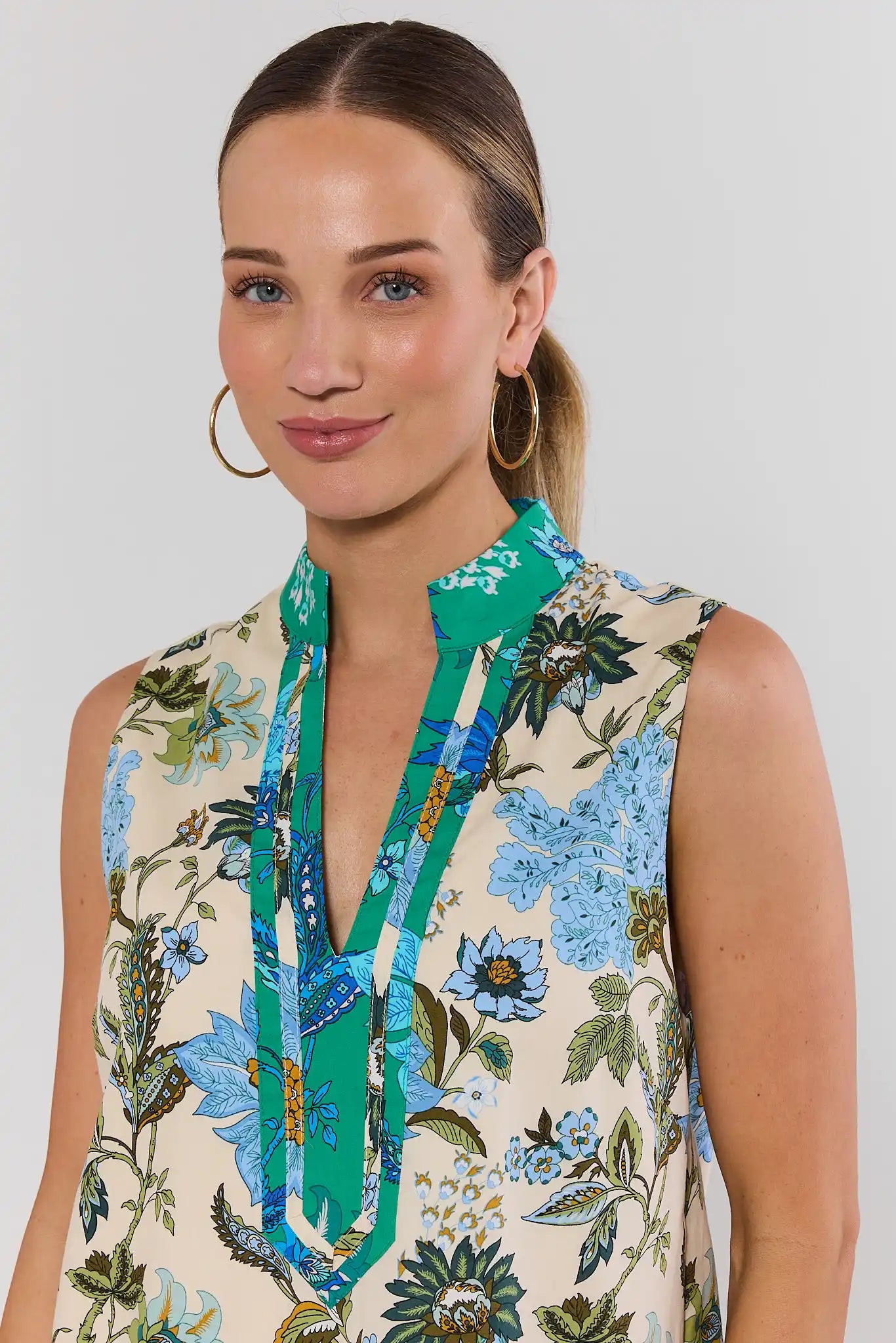 Woman wearing a floral dress with a green collar against a plain background close up