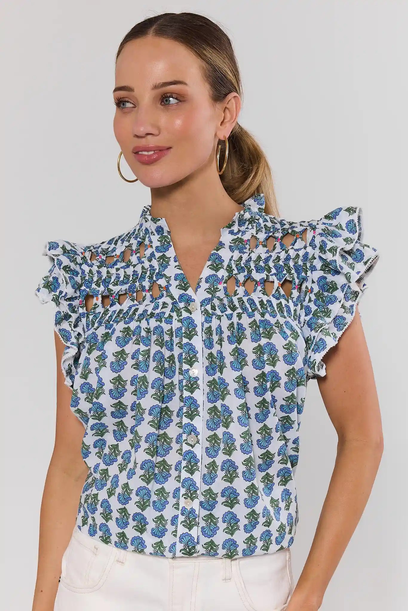 Woman wearing a floral blouse with ruffled sleeves on a plain background