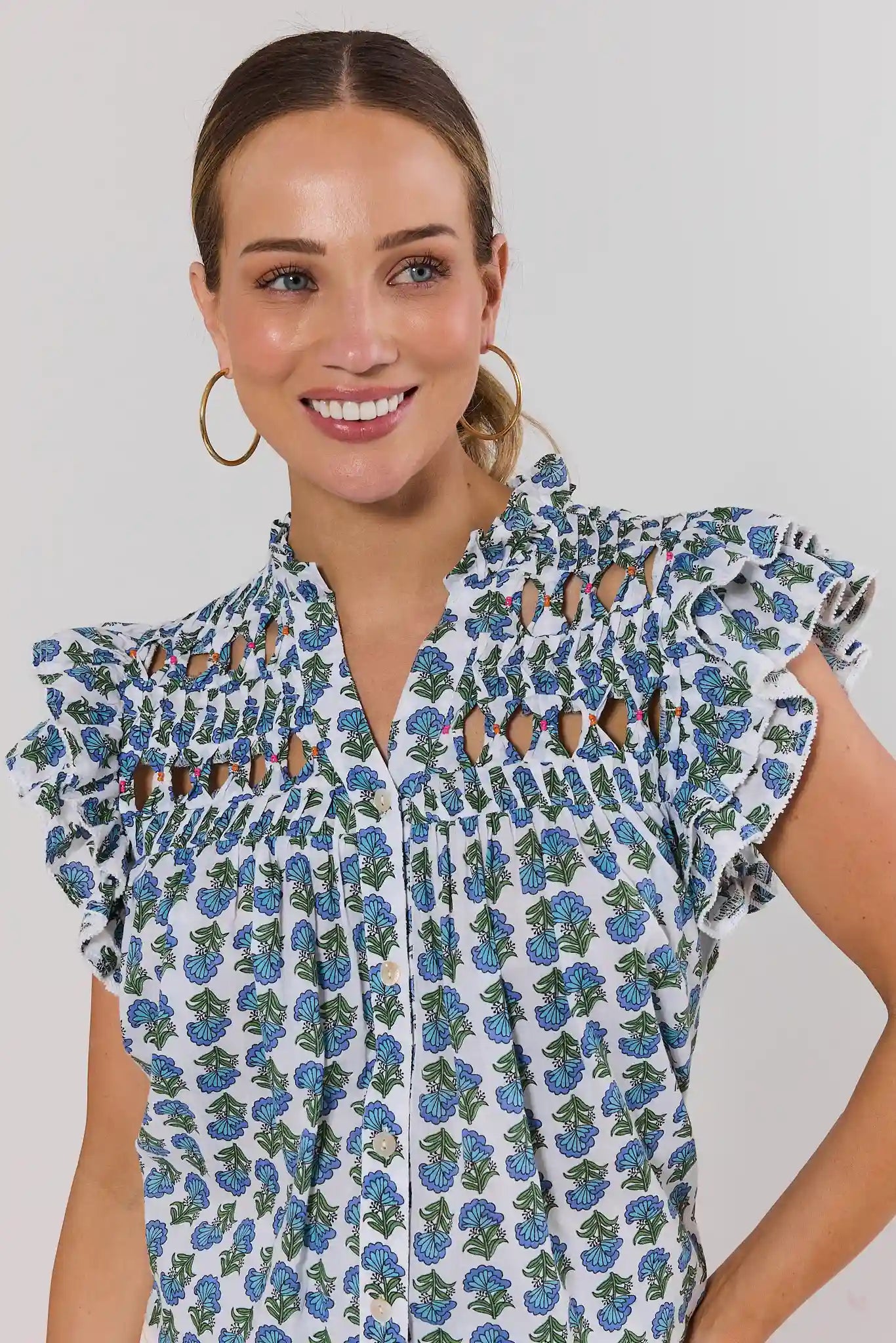 close up Woman wearing a floral blouse with ruffled sleeves against a plain background
