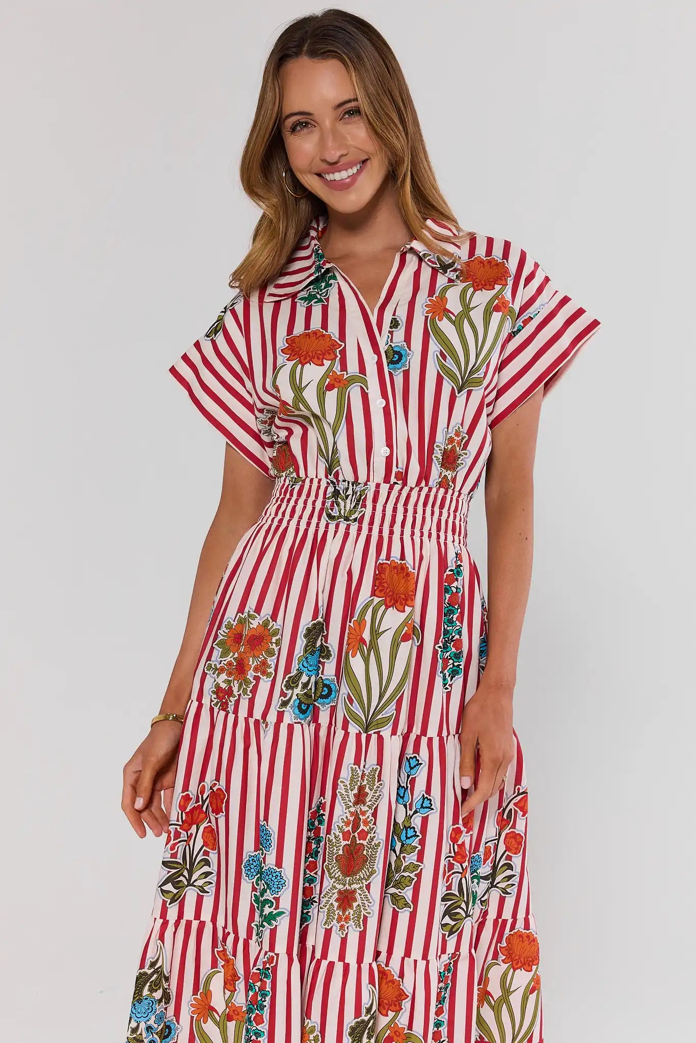 Woman wearing a red and white striped dress with floral patterns on a plain background