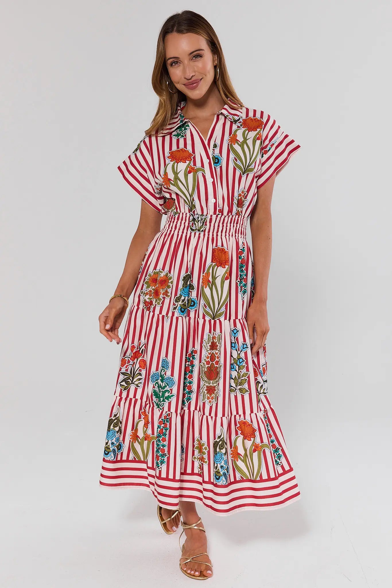 Woman wearing a red and white striped dress with floral patterns on a white background full body