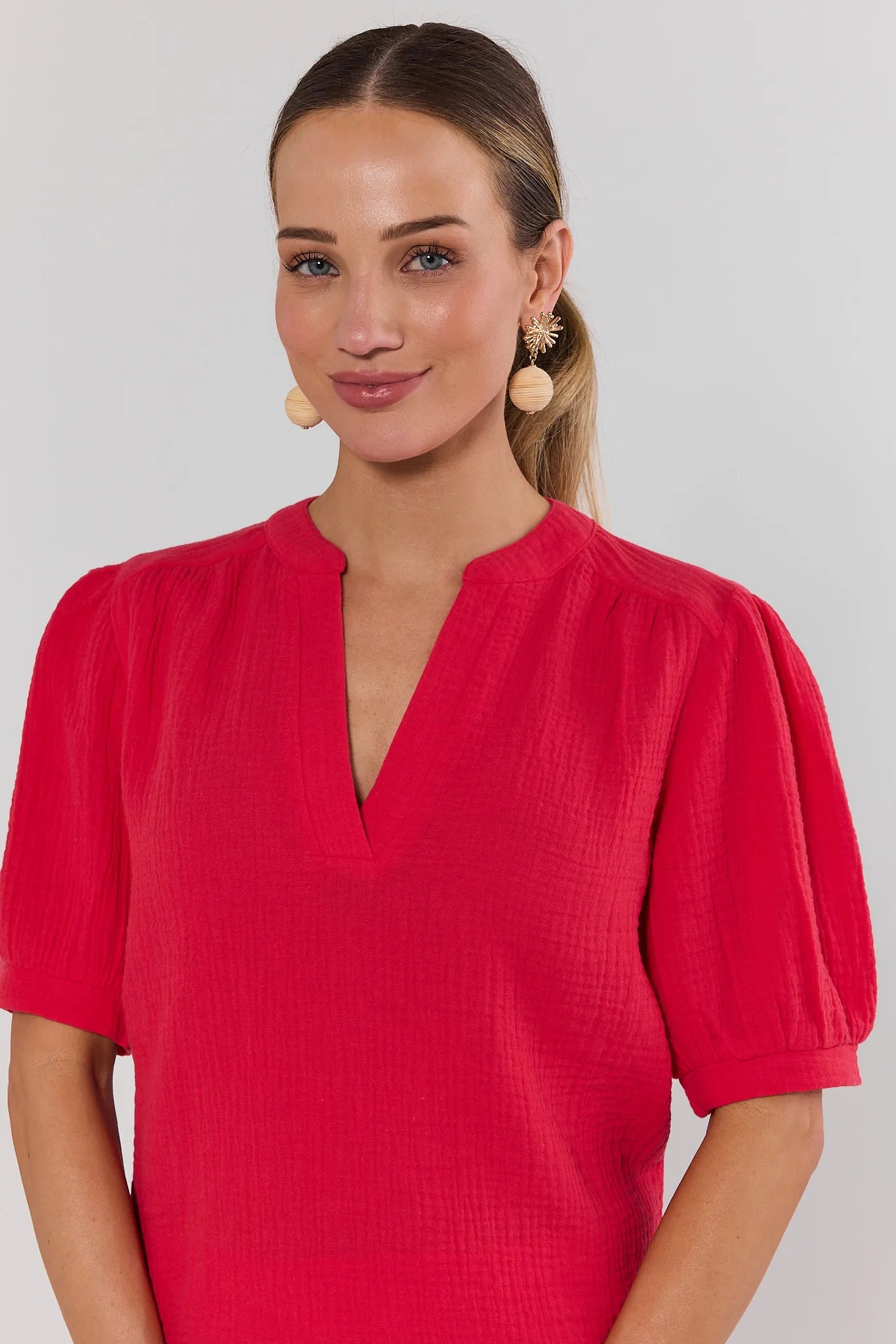 close up Woman wearing a red dress with puff sleeves against a plain background