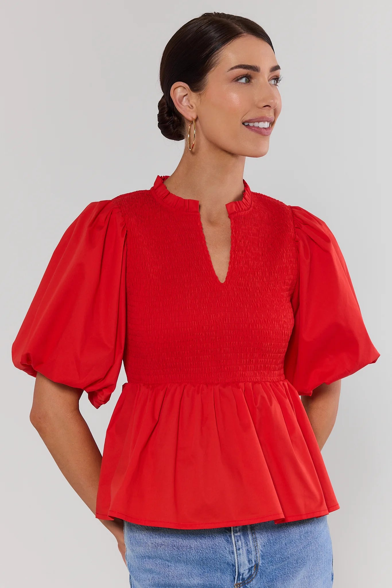 Woman wearing a red blouse with puffed sleeves against a white background