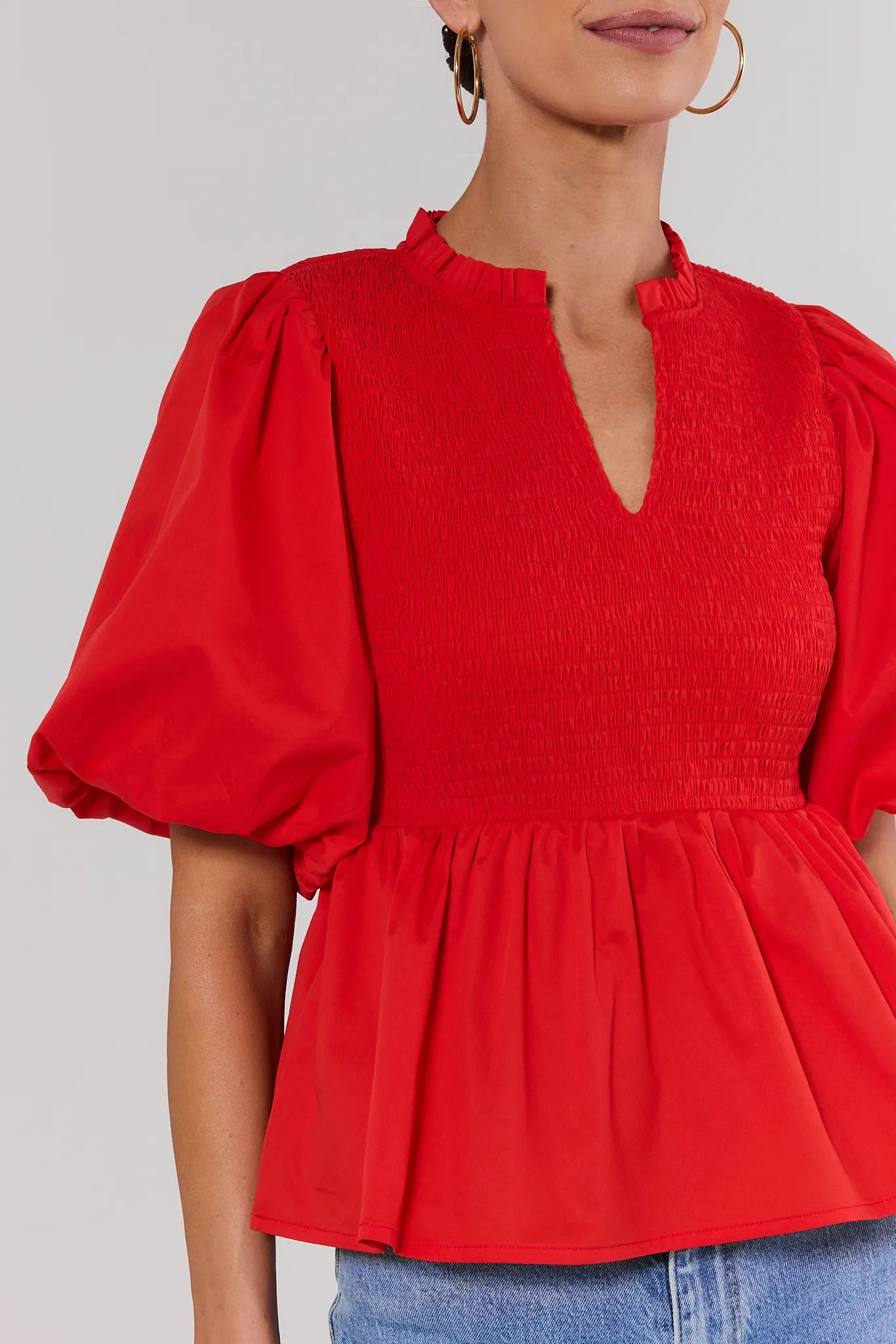 close up Red blouse with puff sleeves worn by a person on a plain background