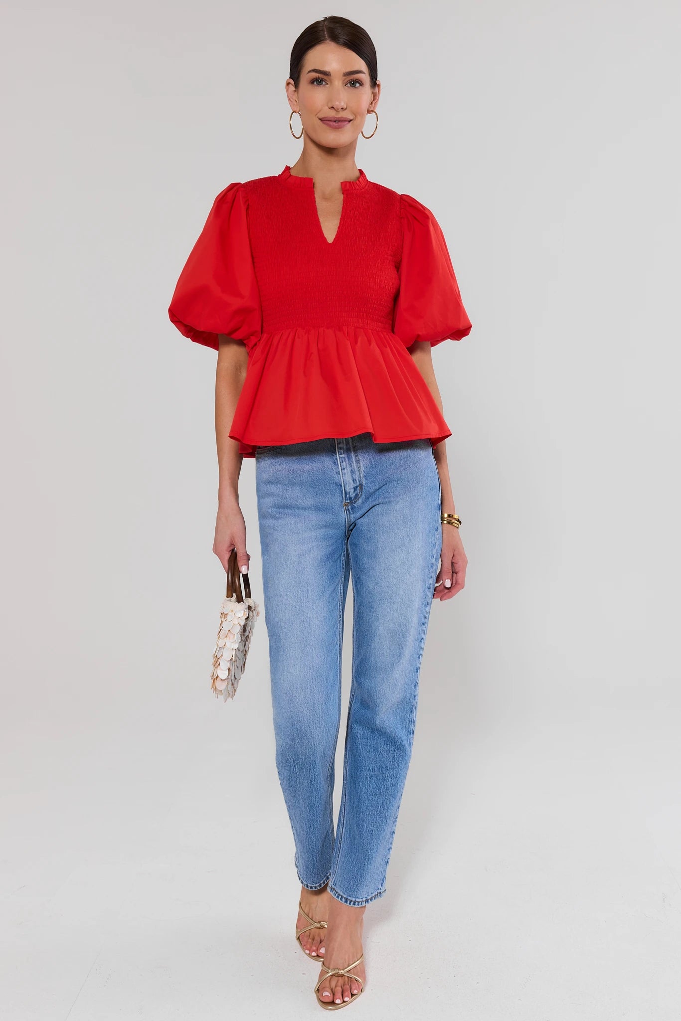 Woman wearing a red blouse and blue jeans on a white background