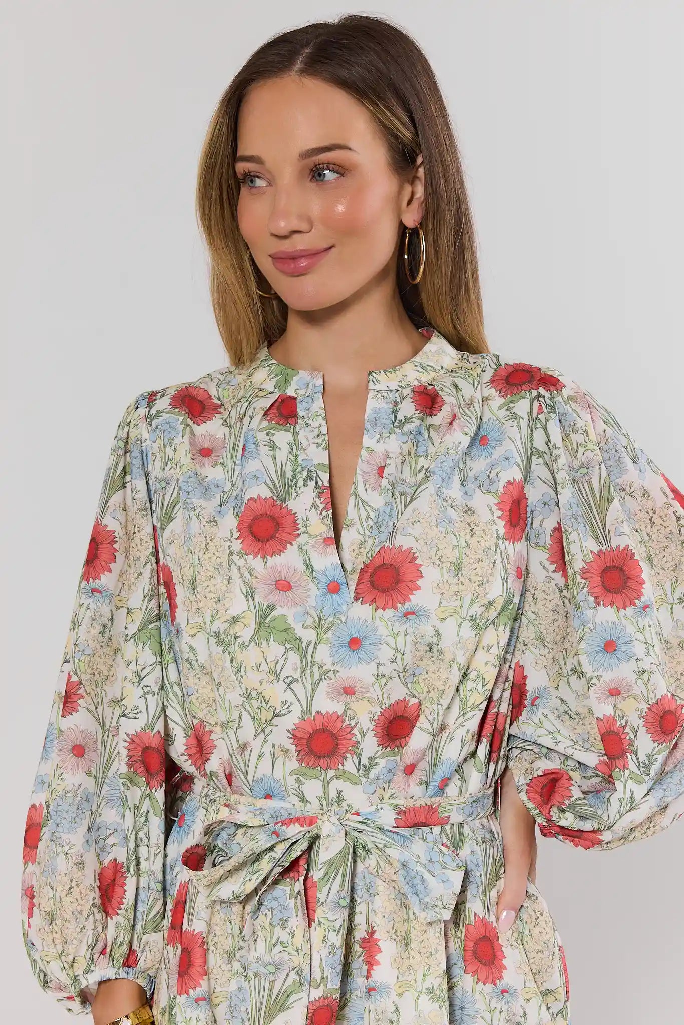 close up Woman wearing a floral dress with red and blue flowers on a plain background