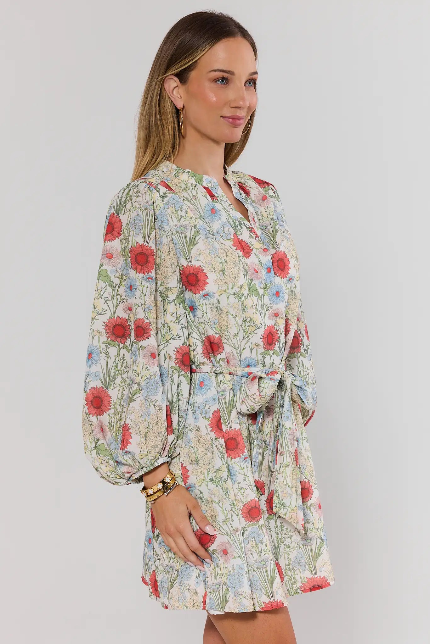Woman wearing a floral dress with long sleeves on a plain background side