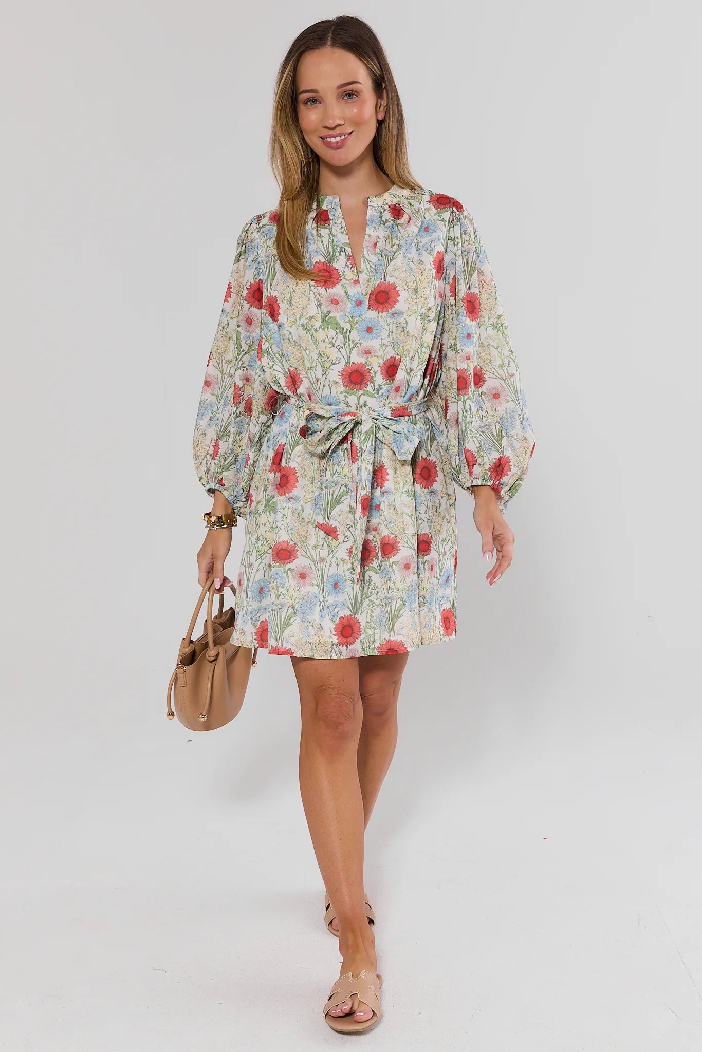 Woman wearing a floral dress with a plain background standing