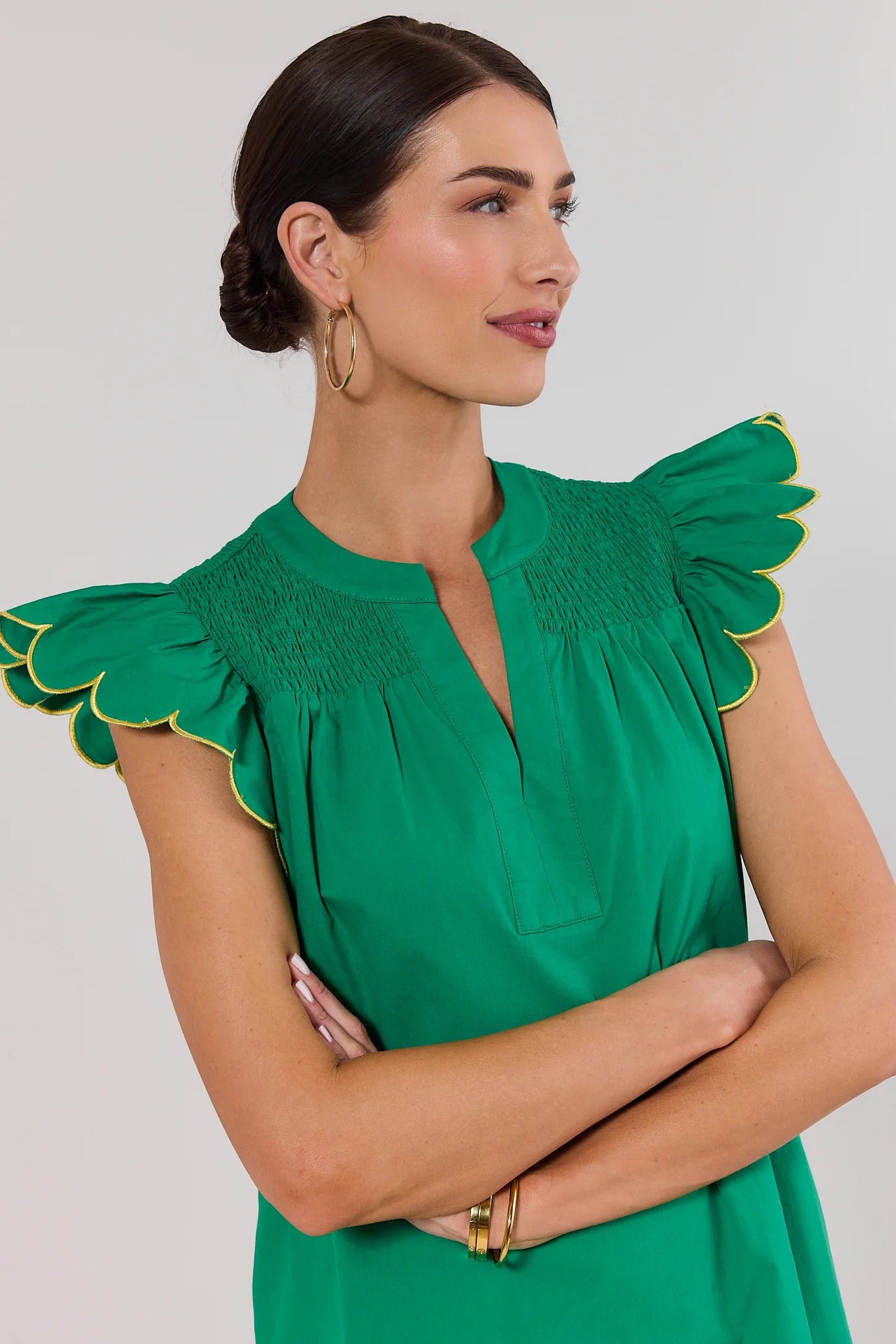 close up Woman wearing a green dress with ruffled shoulders against a plain background