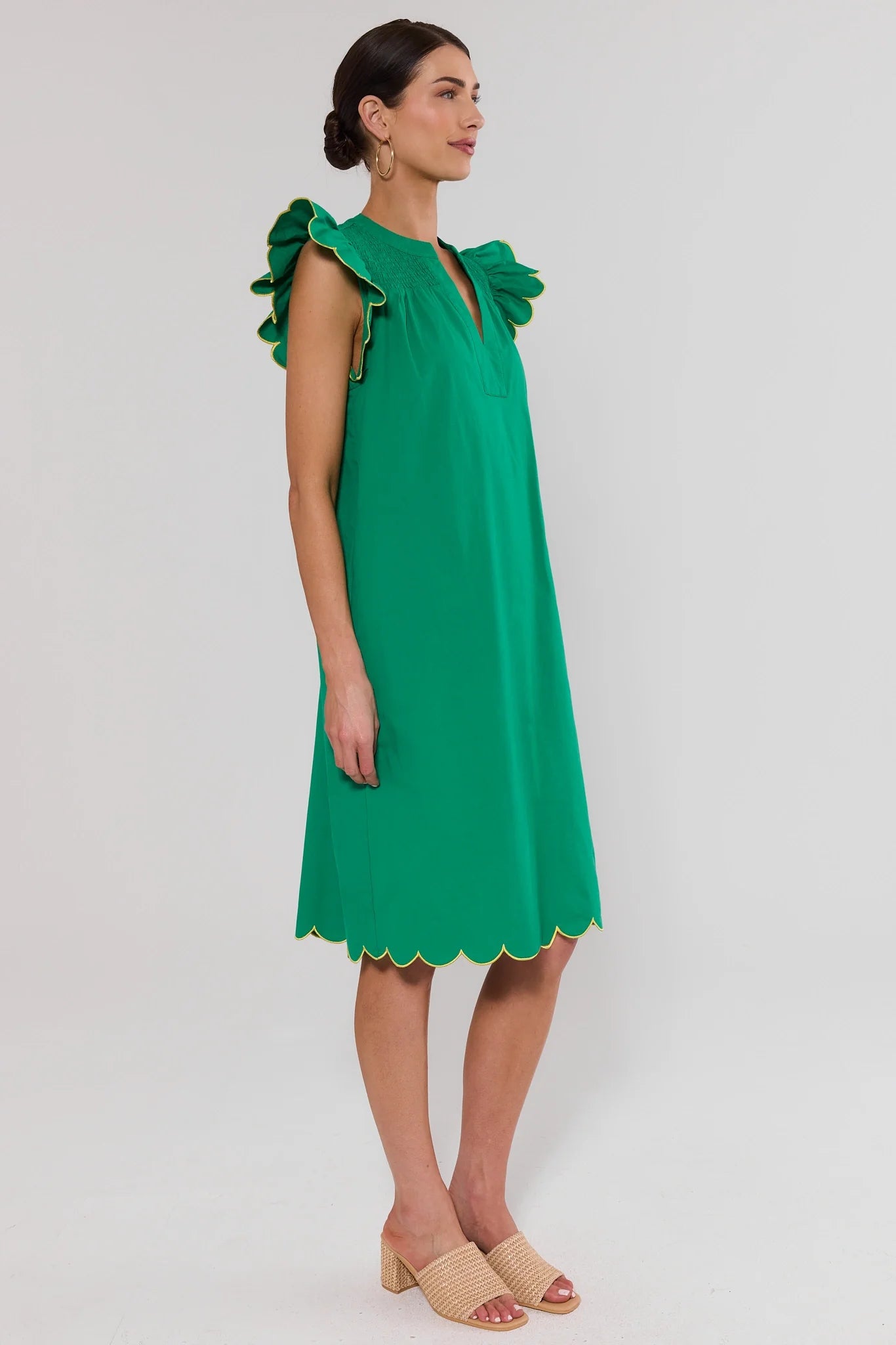 Woman wearing a green dress with ruffled shoulders on a white background side
