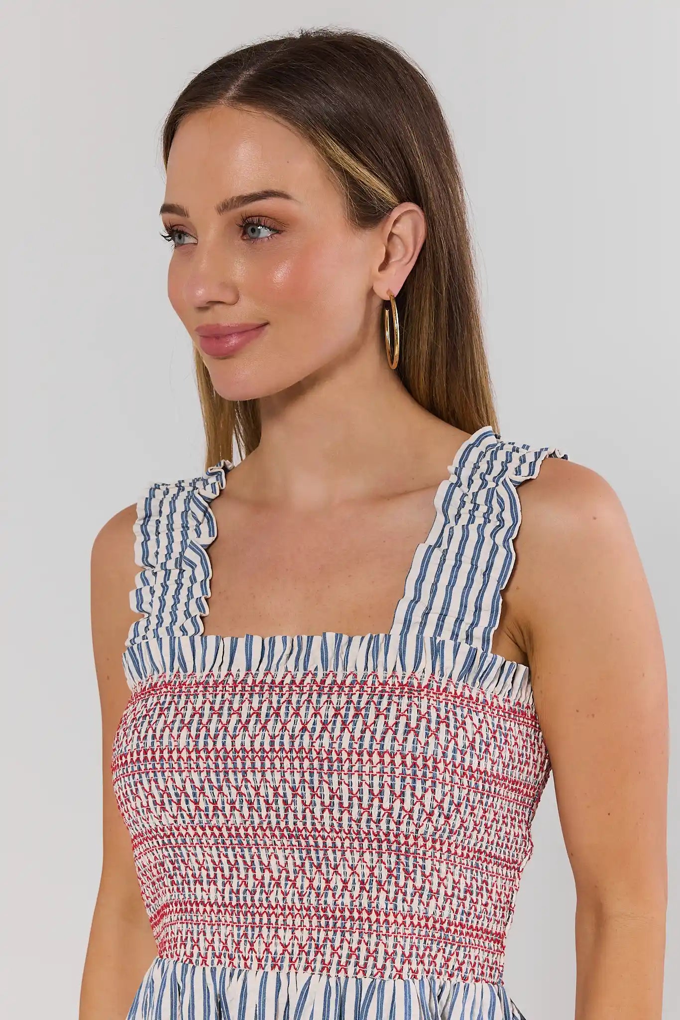 Woman wearing a striped dress with a plain background close up