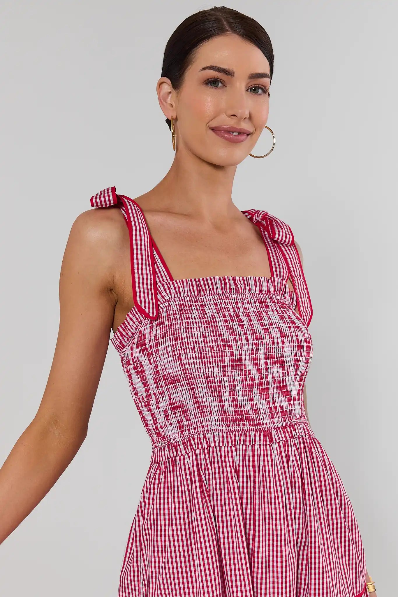 close up Woman wearing a red and white checkered dress against a plain background