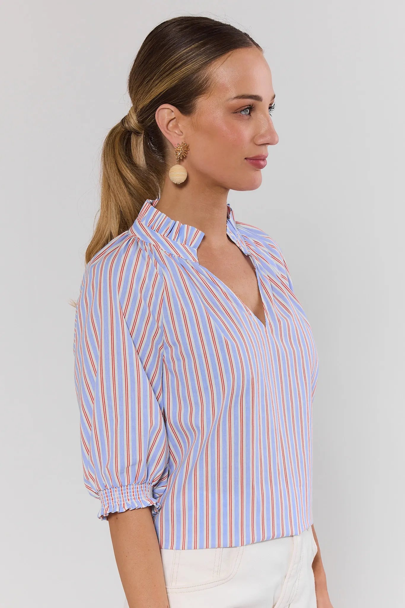 Woman wearing a striped shirt with a plain background side