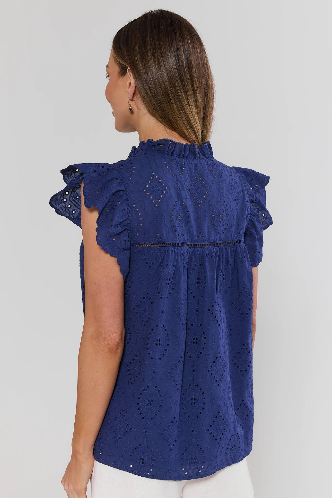 Woman wearing a blue blouse with ruffled sleeves on a white background stand