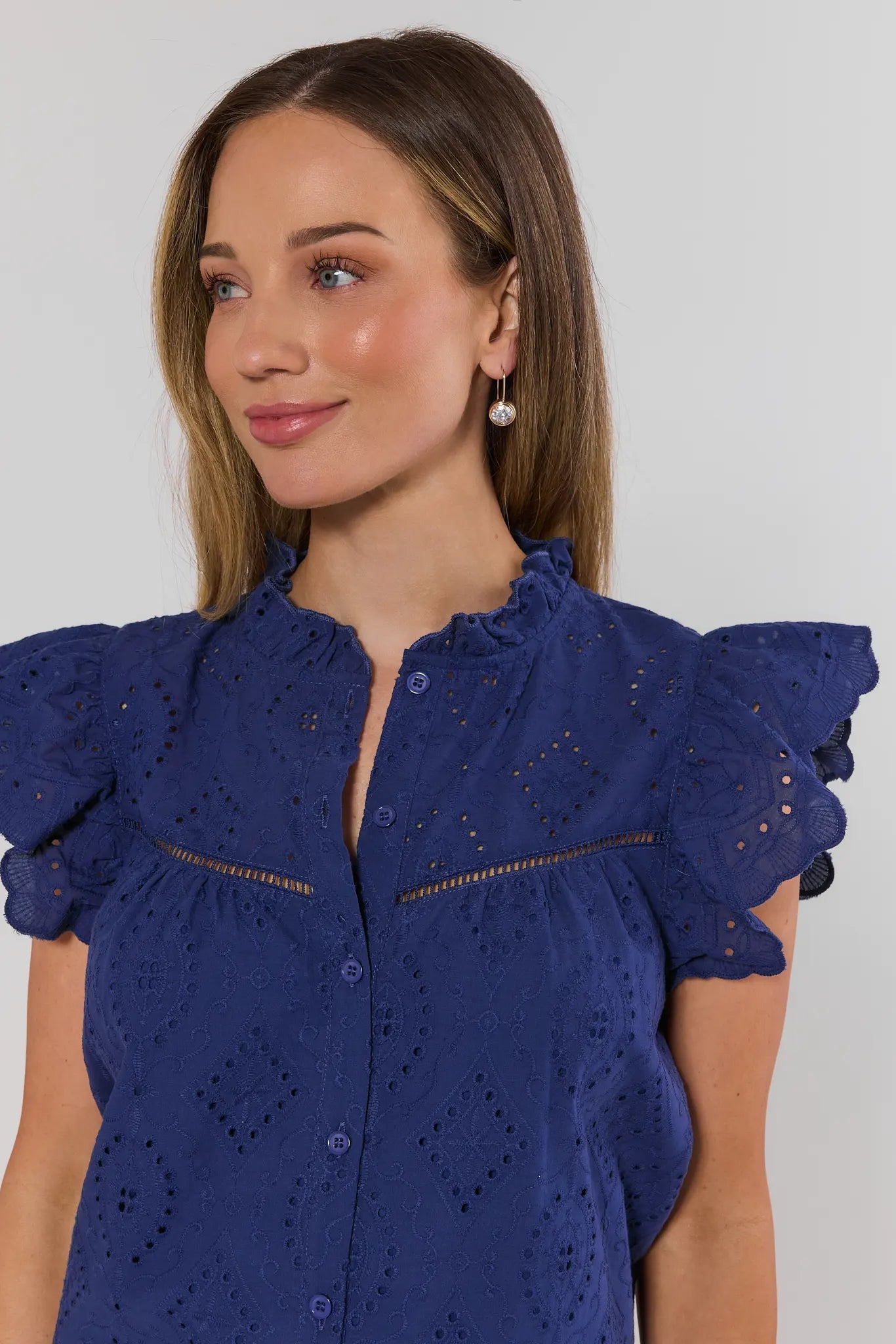 close up Woman wearing a blue blouse with ruffled sleeves against a white background