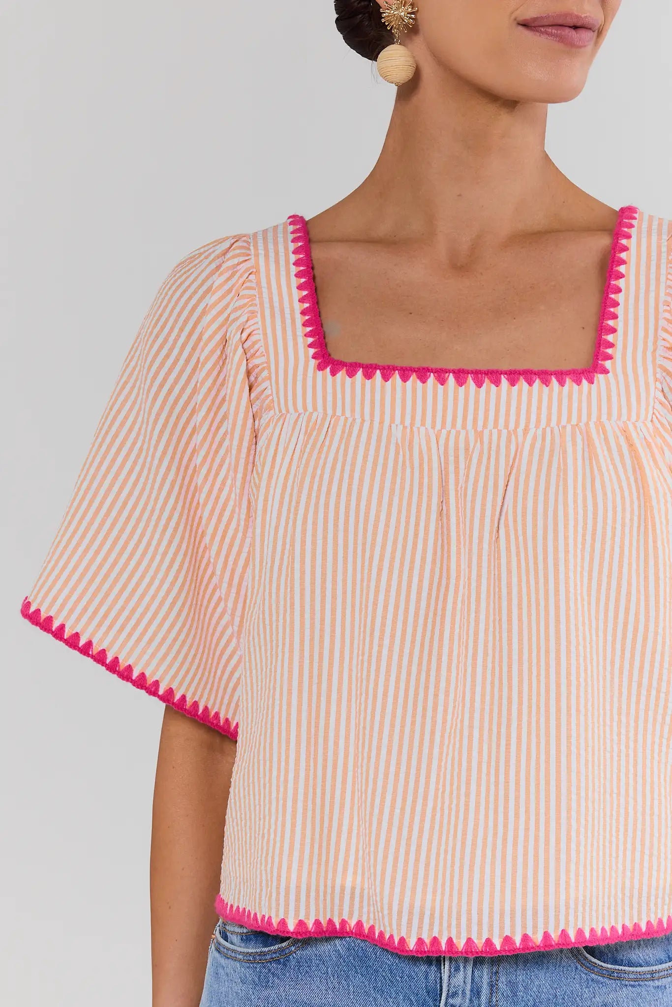 close up Woman wearing a striped top with pink trim on a plain background