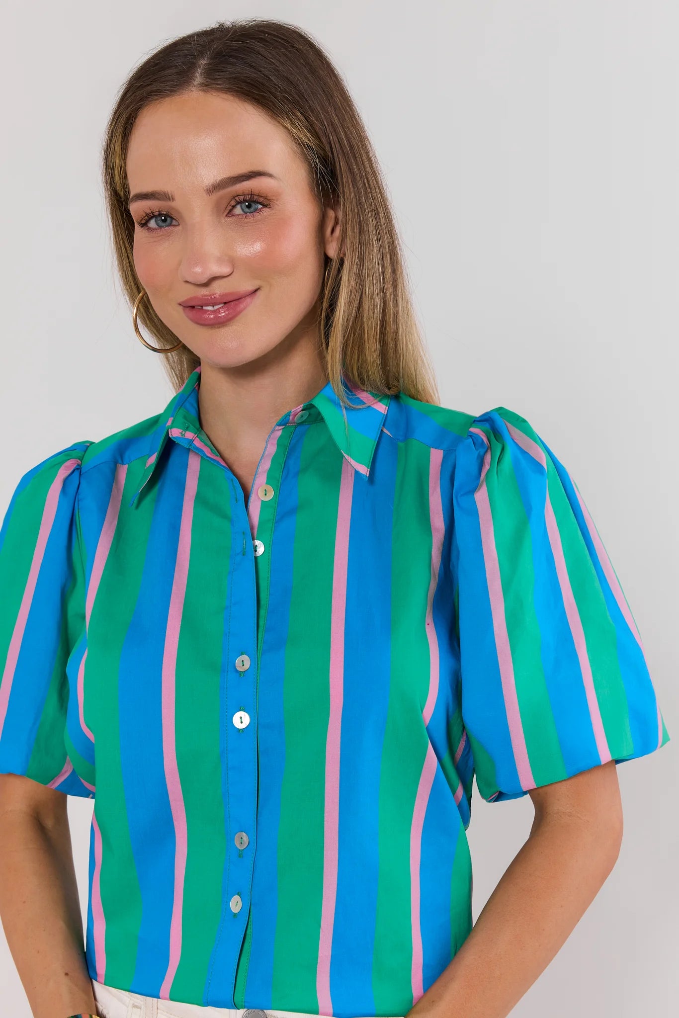 close up Woman wearing a colorful striped shirt against a plain background