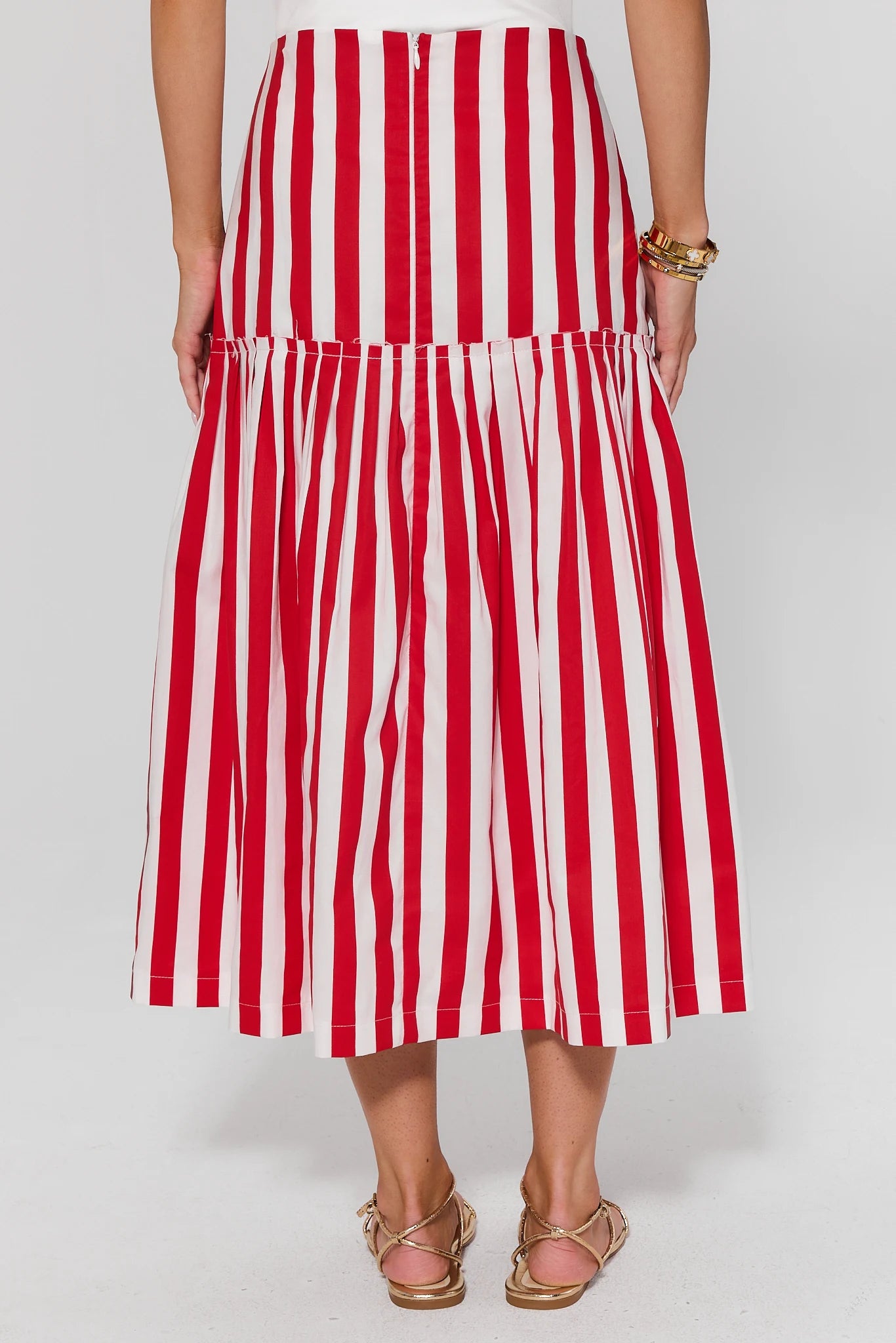 Red and white striped skirt worn by a person on a plain background standing
