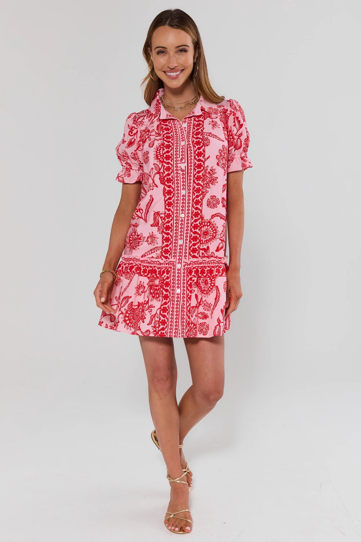 Woman wearing a red and white patterned dress on a white background standing