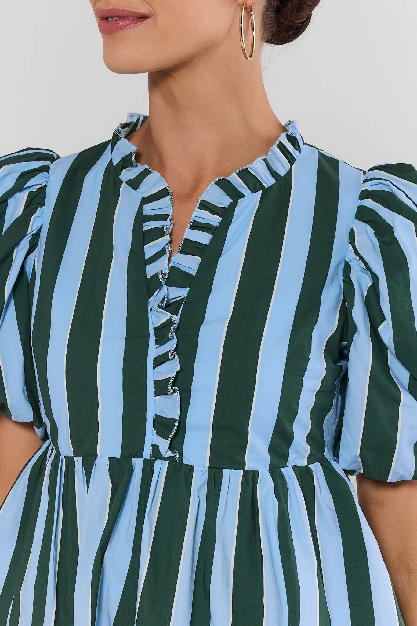 Close-up of a person wearing a green and blue striped dress with ruffled details.