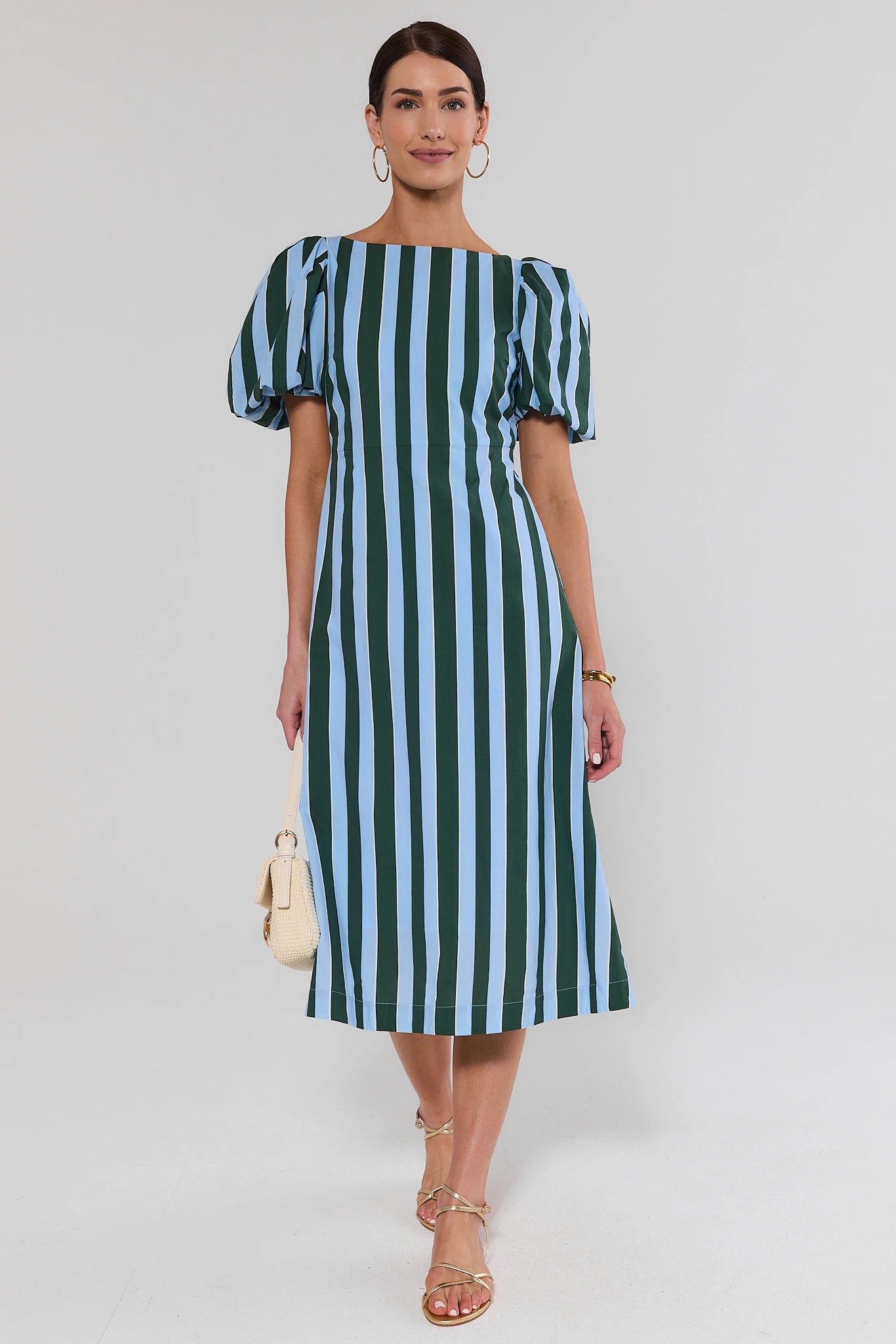 Woman wearing a green and blue striped dress on a white background standing