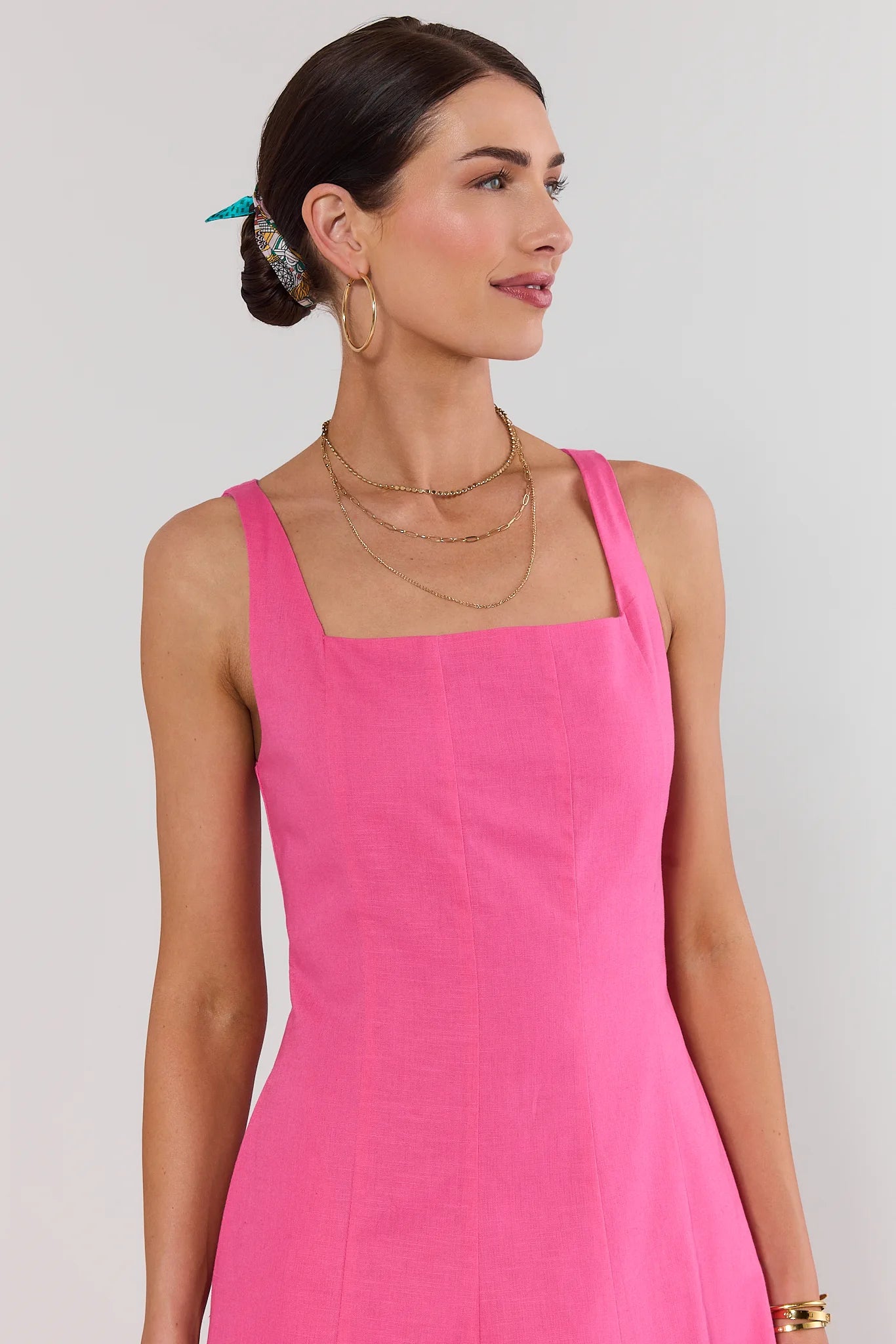 Woman wearing a pink dress against a plain background close up