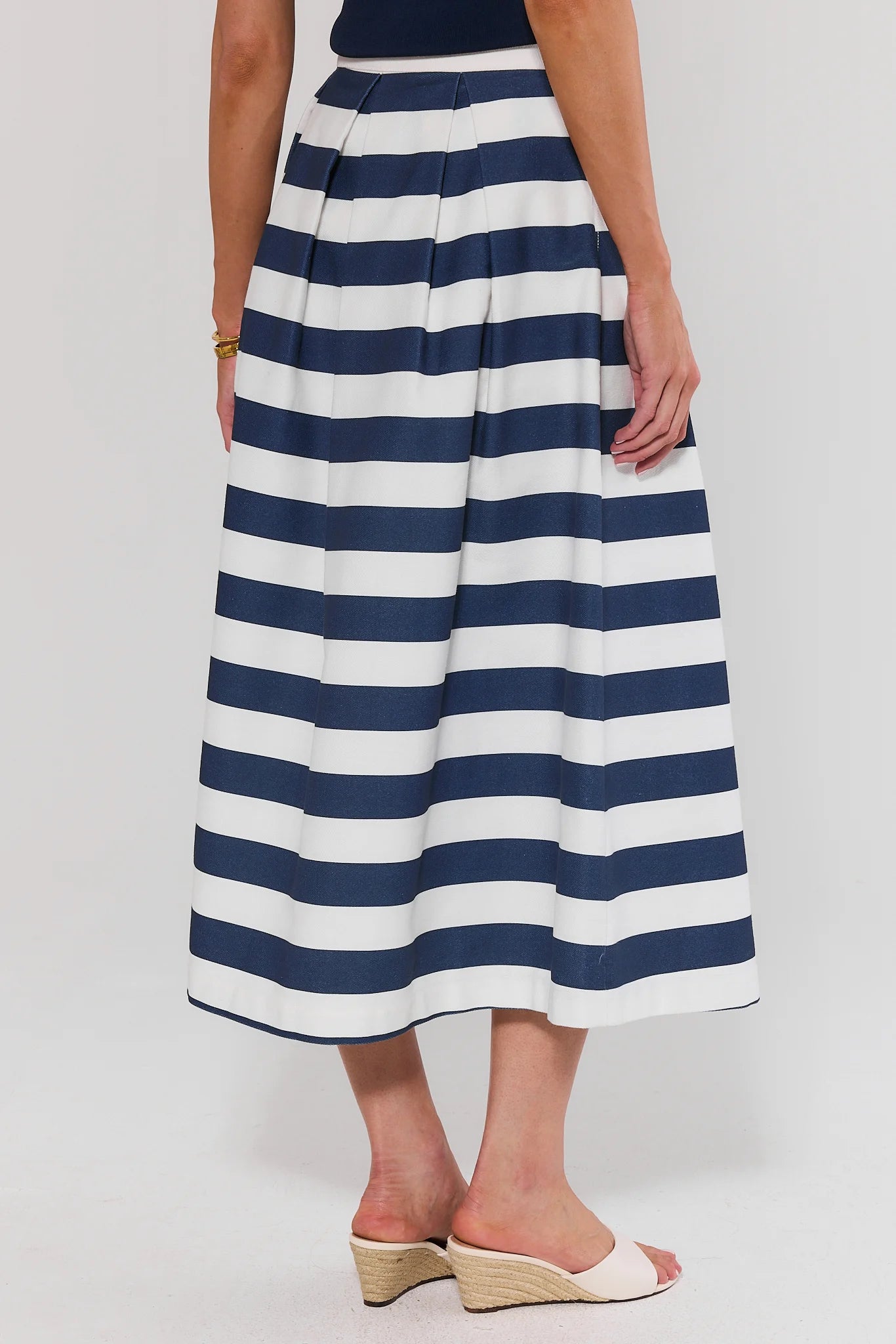 Person wearing a navy and white striped skirt standing on a plain background
