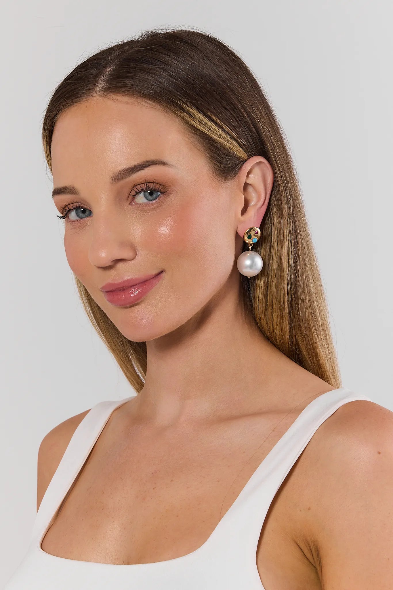 Woman wearing pearl earrings against a plain background