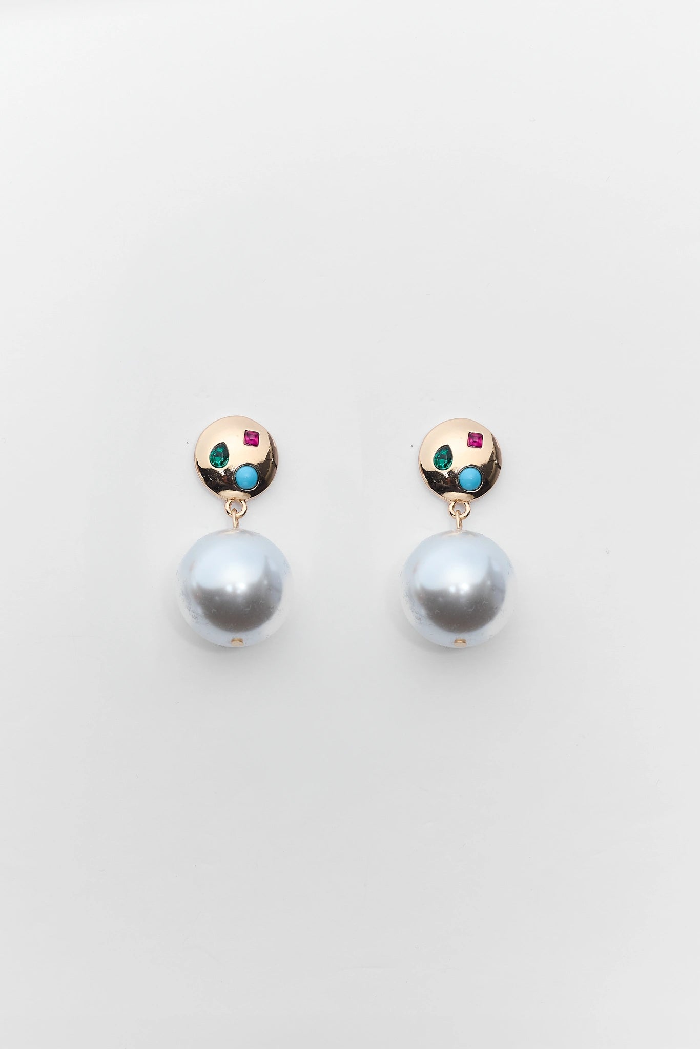 Pair of pearl earrings with gemstone accents on a light gray background