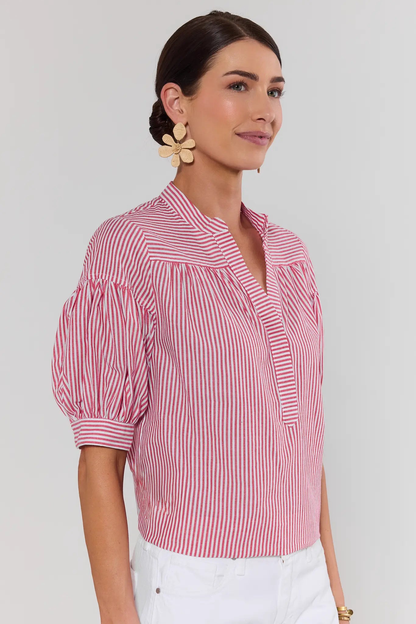 Woman wearing a red and white striped blouse against a plain background side