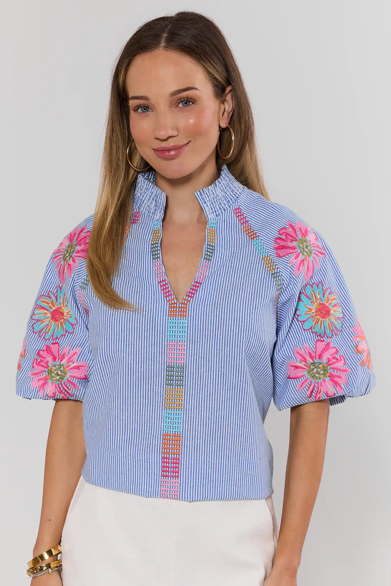 Woman wearing a blue blouse with floral patterns on a plain background
