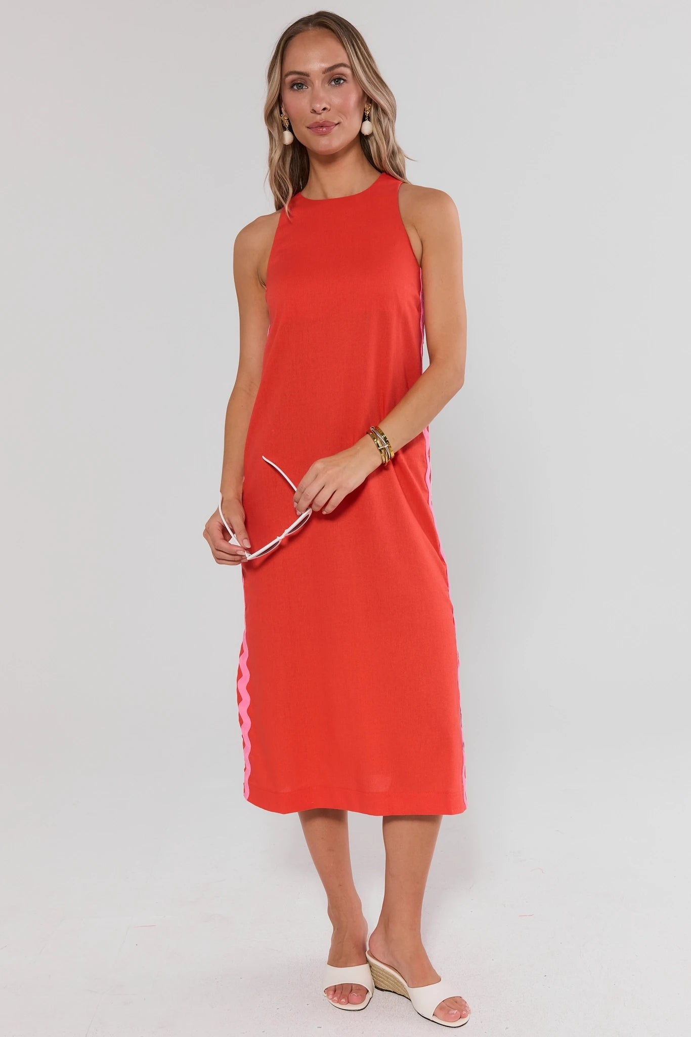Woman wearing a red sleeveless dress on a white background standing