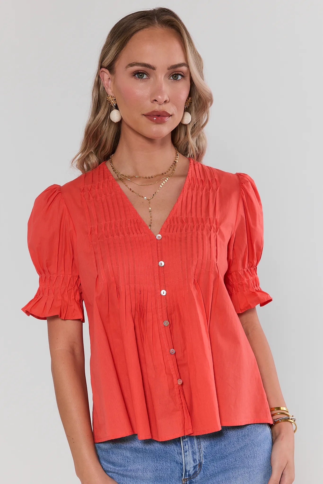 Woman wearing a orange blouse with puff sleeves against a plain background