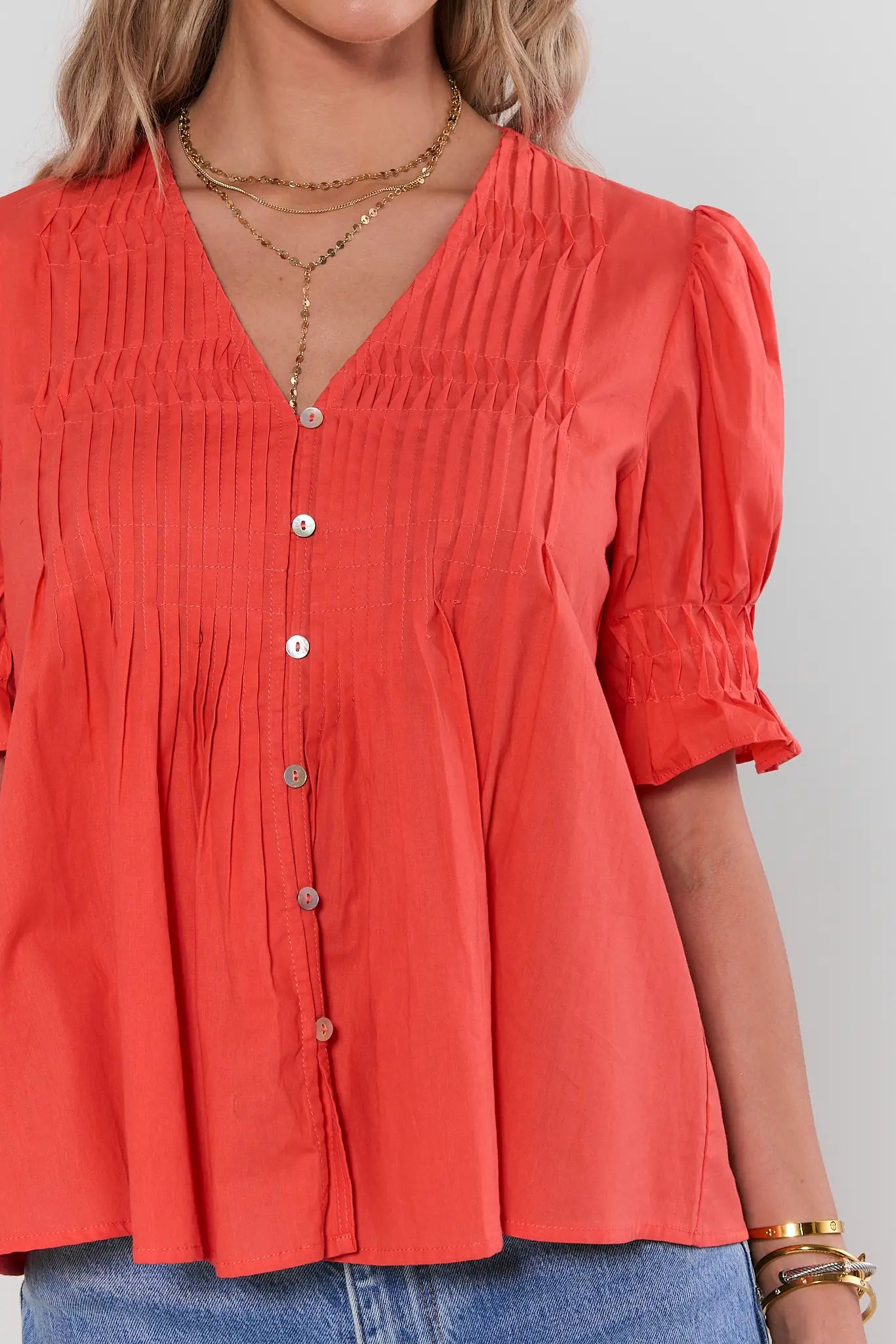 close up Woman wearing a red blouse with puff sleeves on a gray background