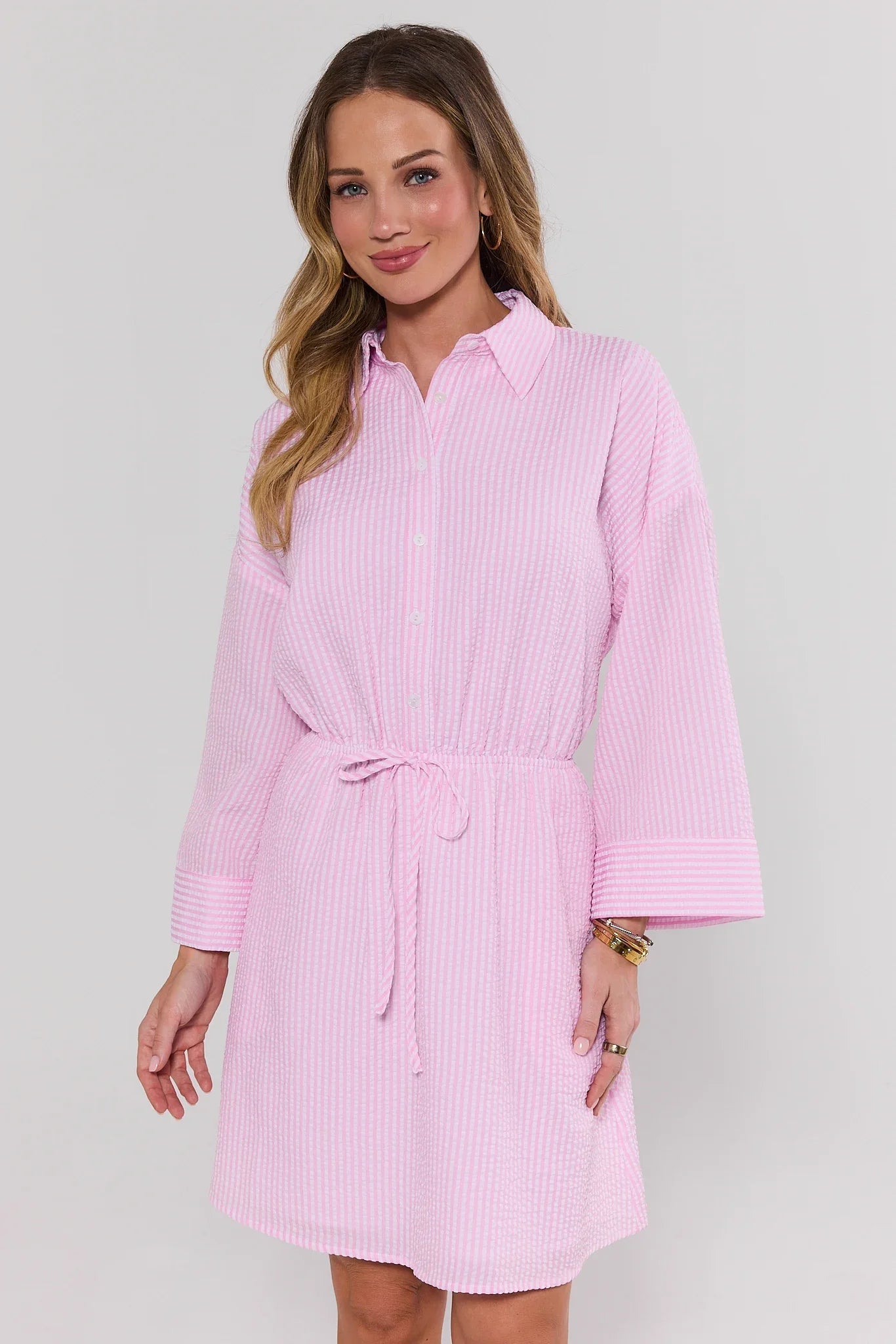 Woman wearing a pink striped dress against a plain background