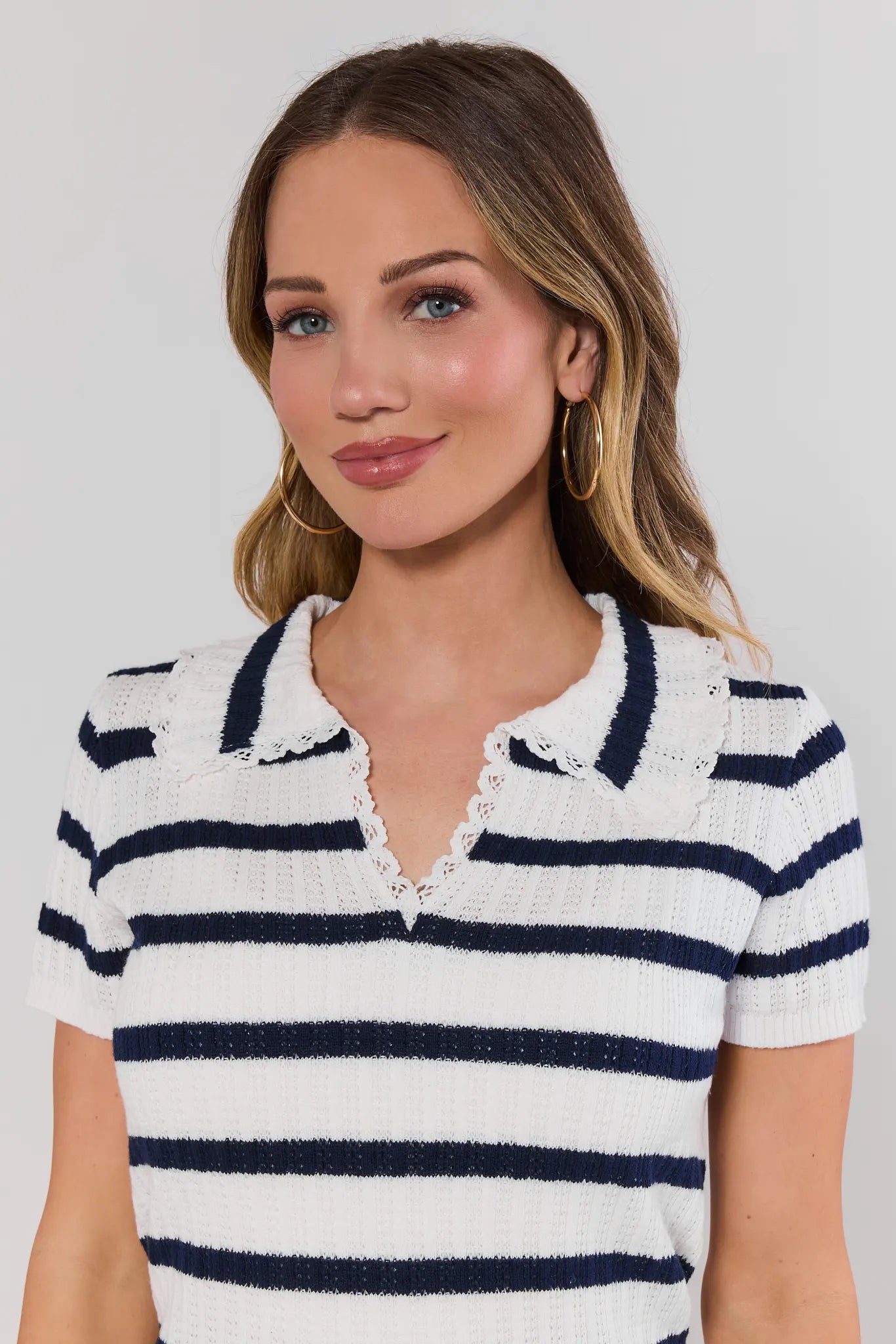 close up Woman wearing a white and navy striped shirt against a plain background