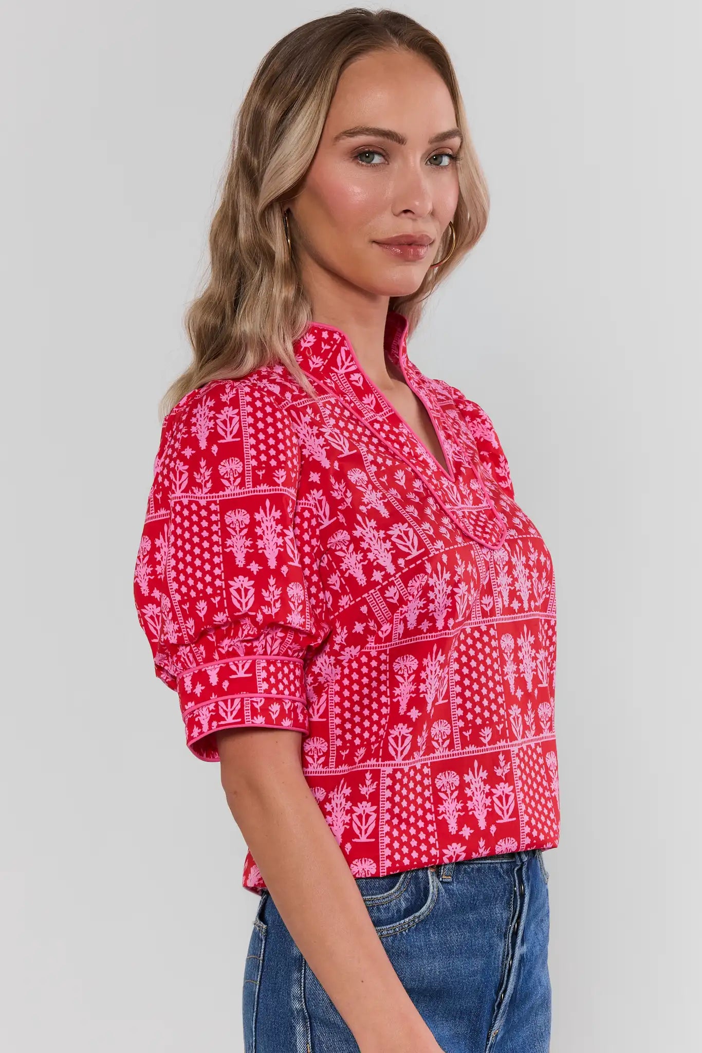 side Woman wearing a red patterned blouse against a plain background