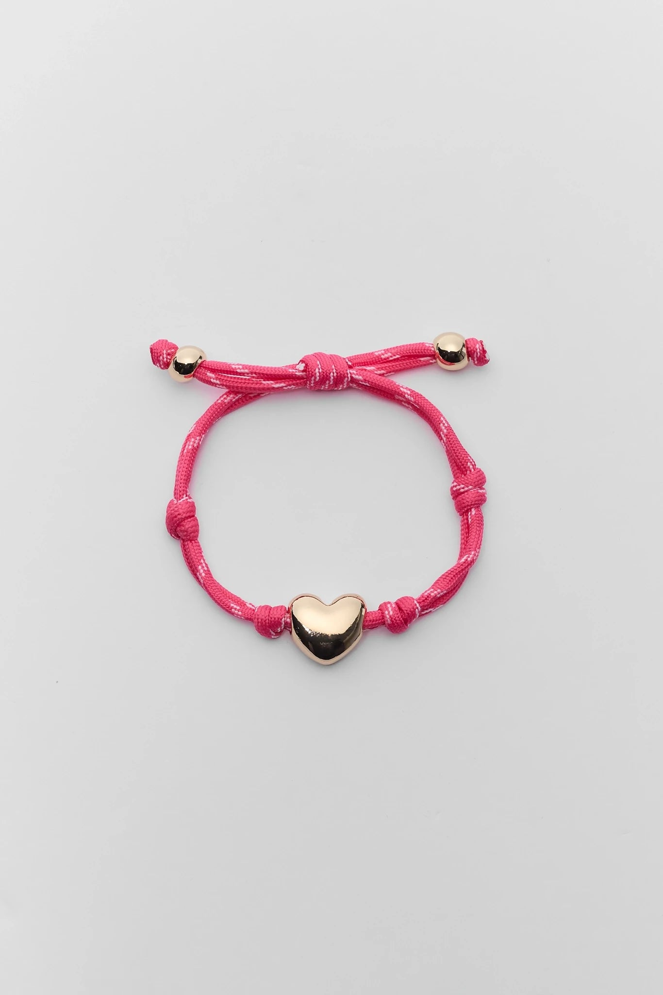 Pink bracelet with a heart-shaped charm on a light gray background