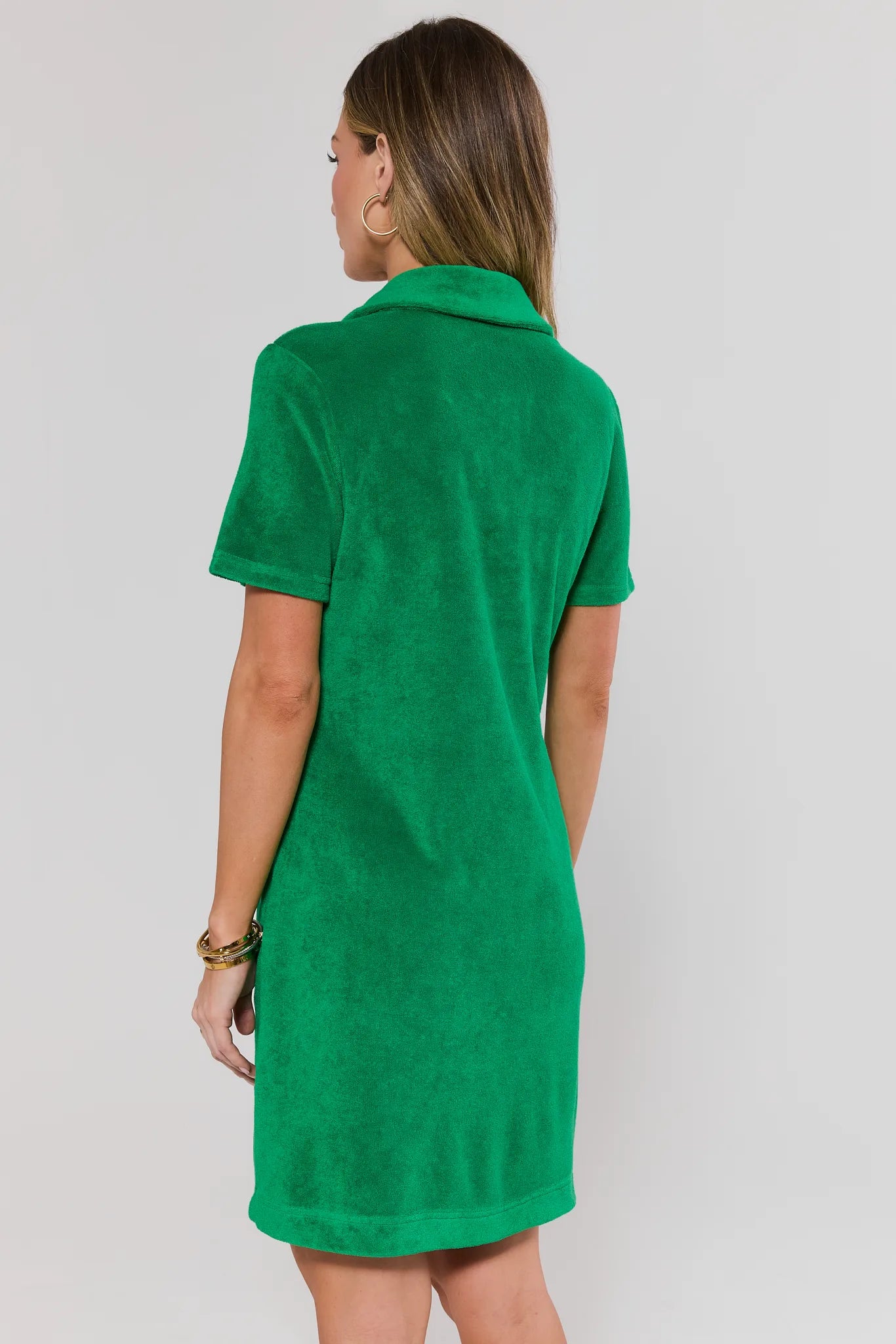 Woman stand wearing a green dress against a plain background