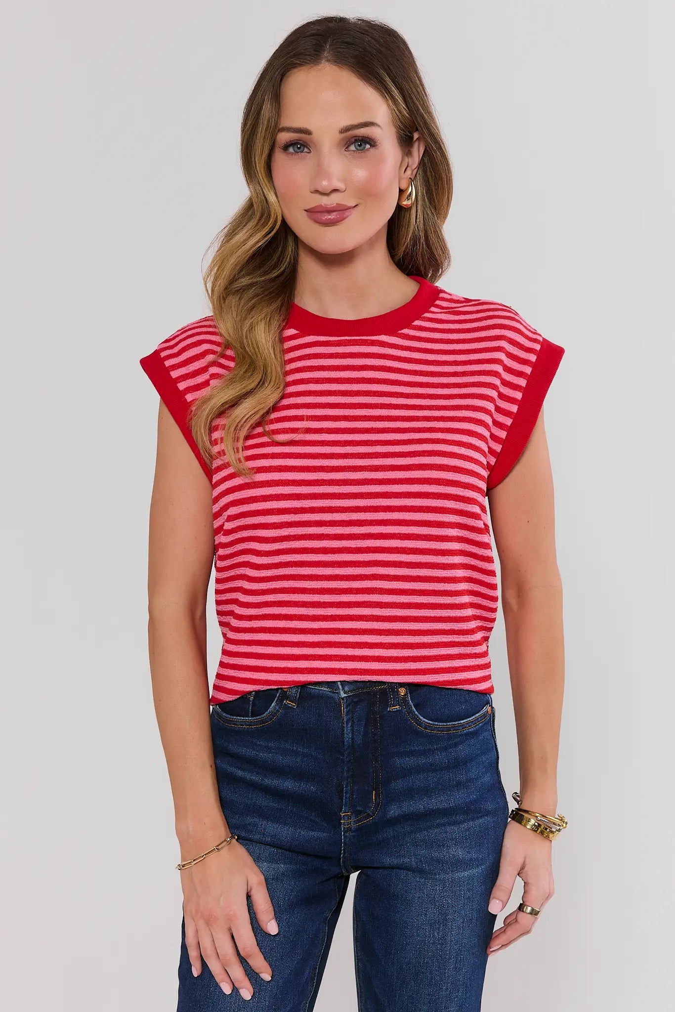 Woman wearing a red and white striped shirt and blue jeans on a plain background