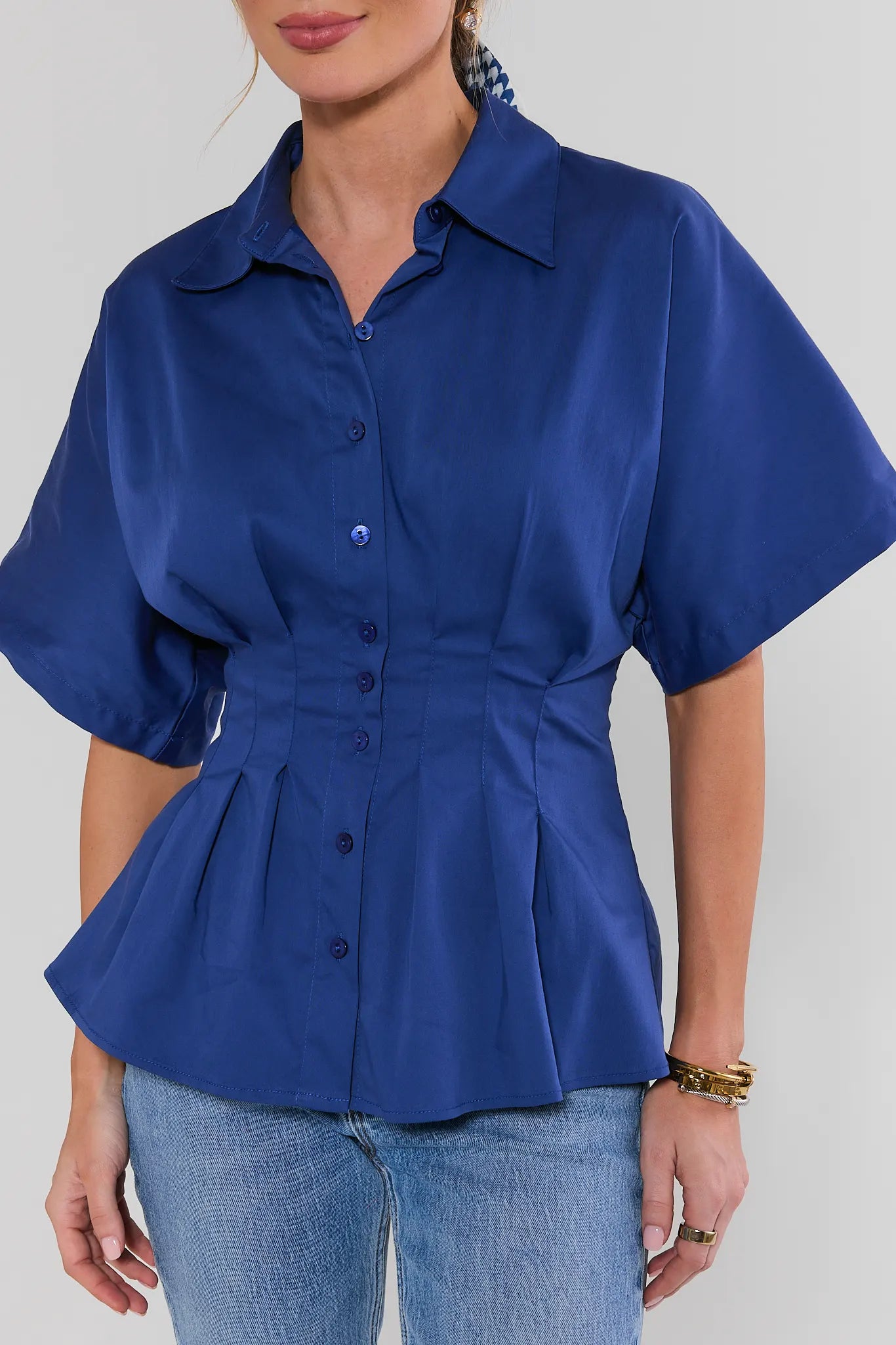 Woman wearing a blue peplum blouse and jeans on a plain background close