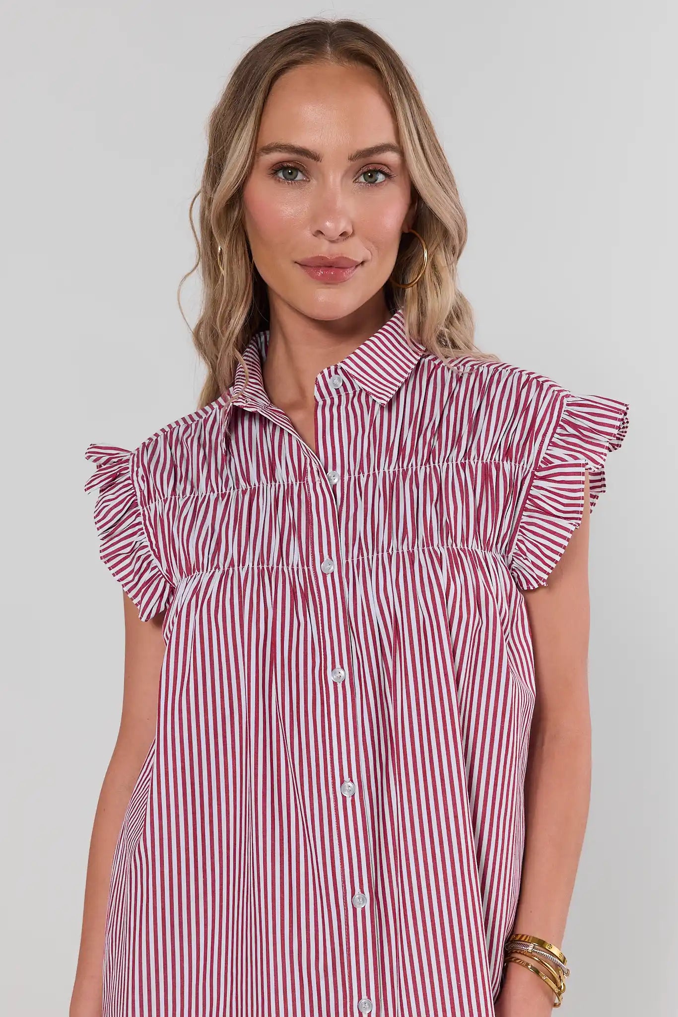 close up Woman wearing a red and white striped dress with ruffled sleeves against a plain background