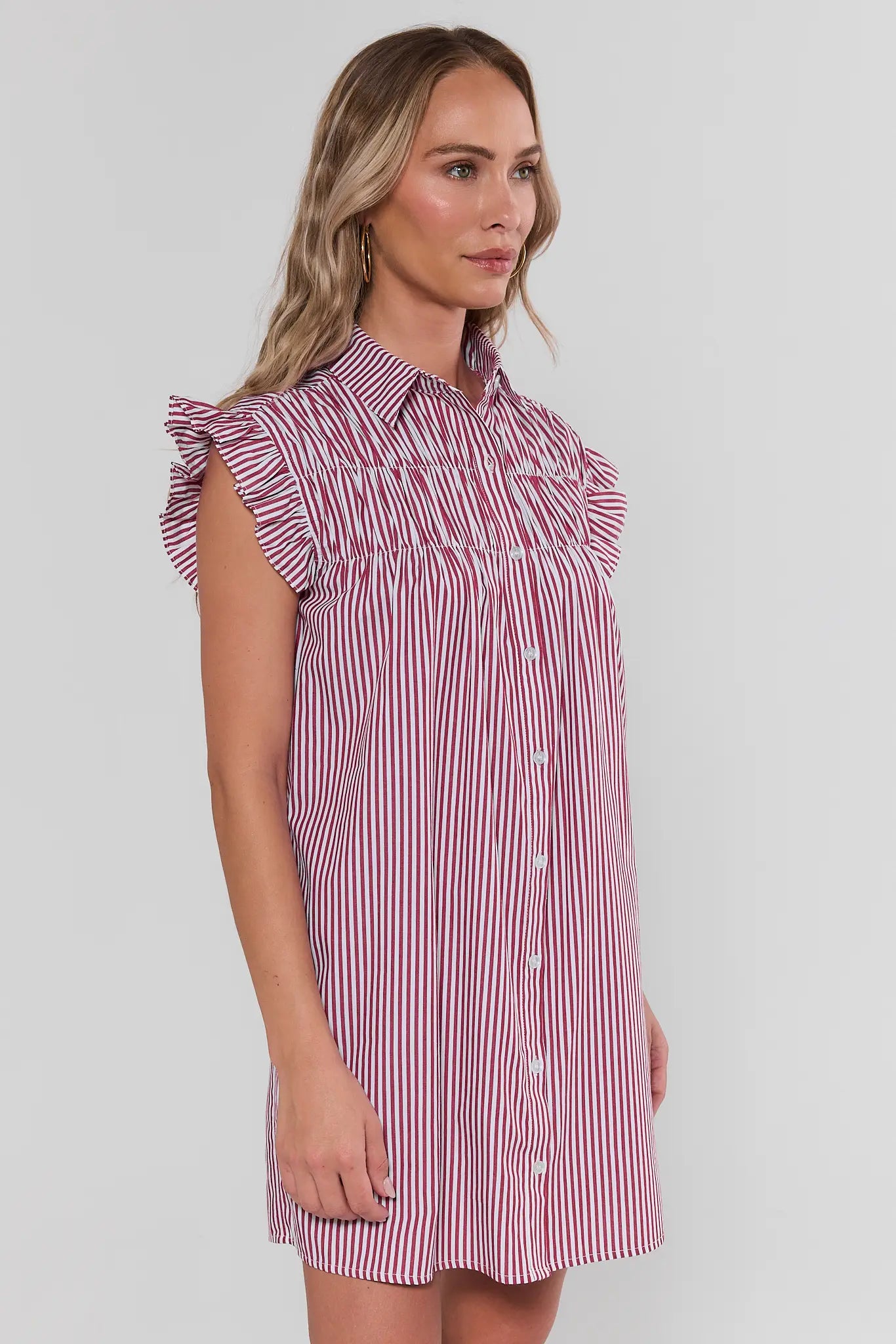 Woman wearing a red and white striped dress against a plain background side