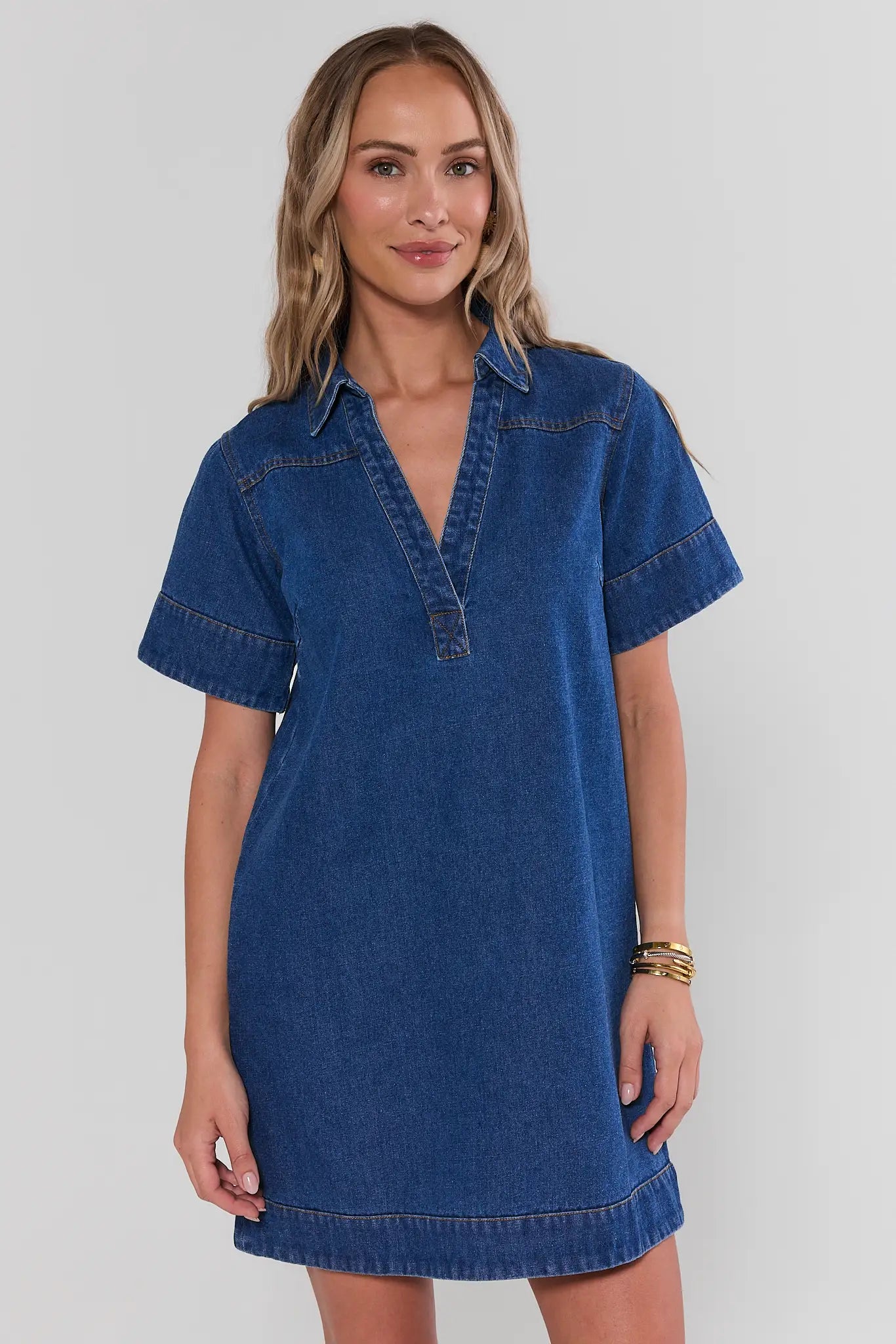 Woman wearing a blue denim dress against a plain background
