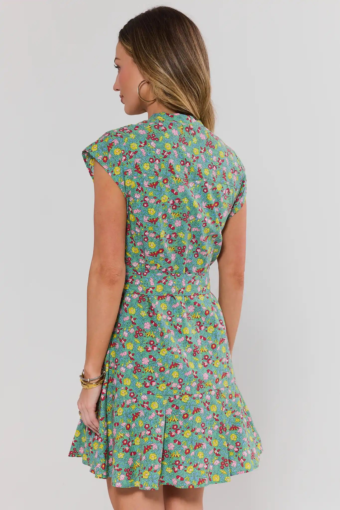 Woman standing wearing a floral dress on a plain background
