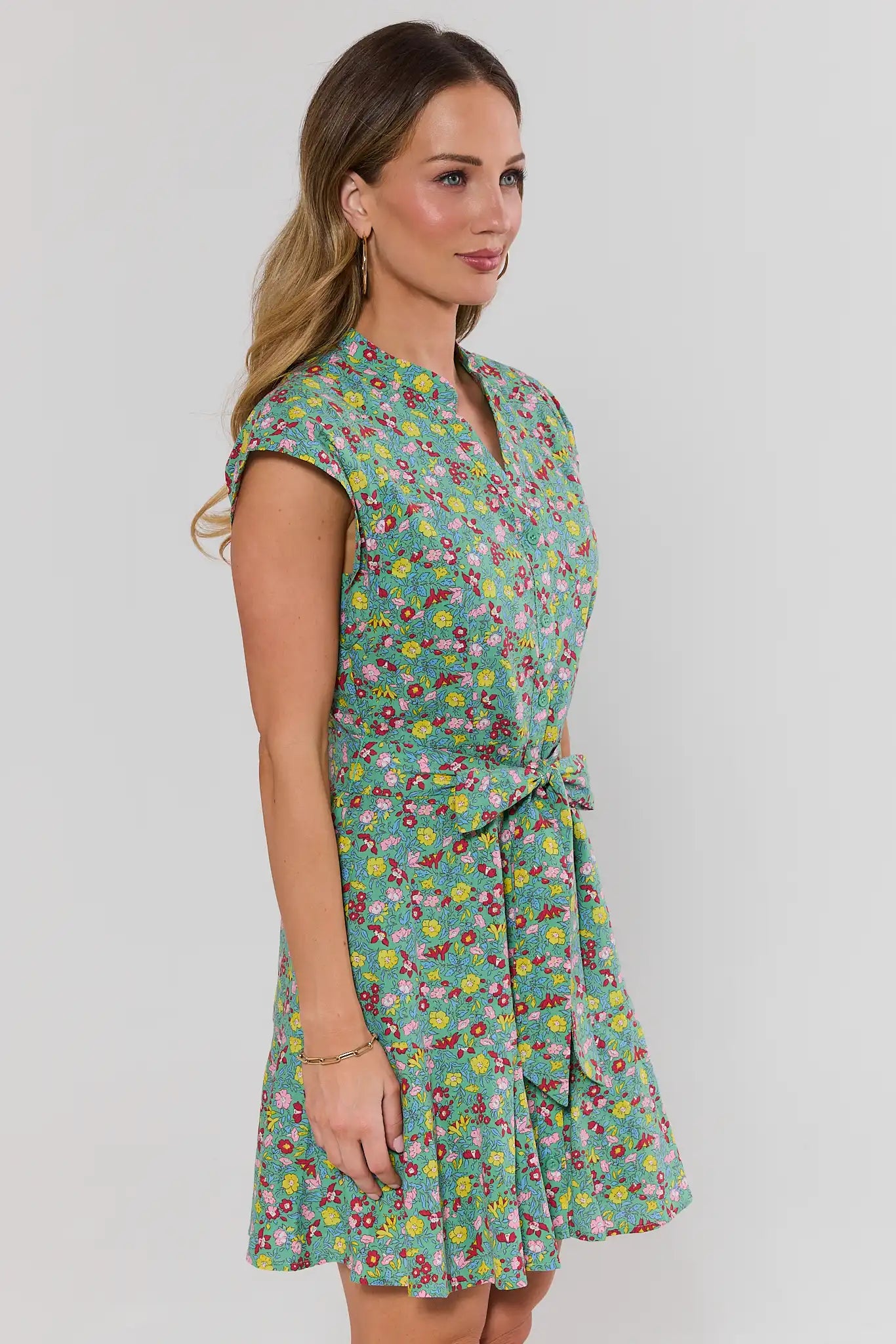Woman wearing a floral dress on a plain background side