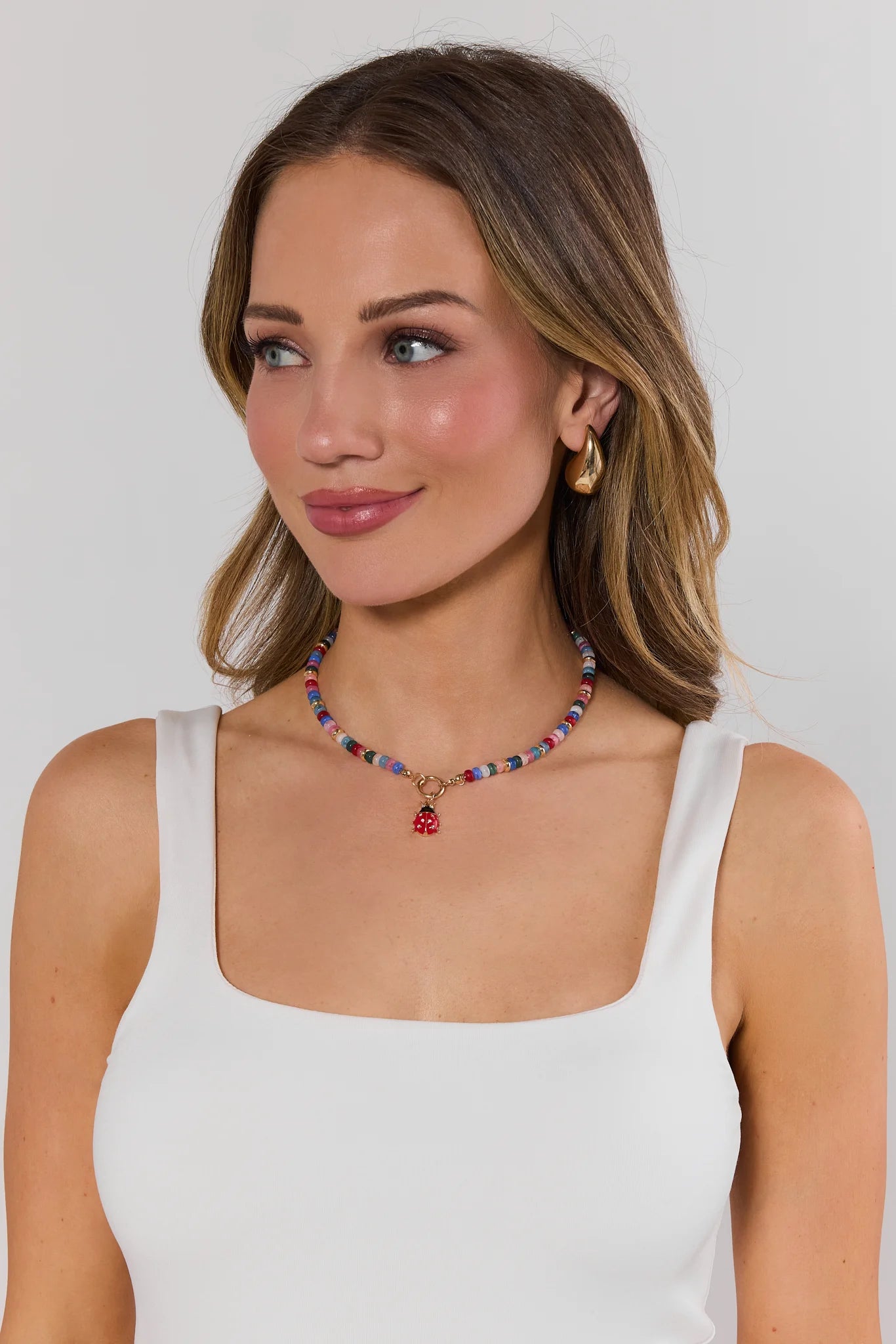 Woman wearing a colorful beaded necklace against a plain background