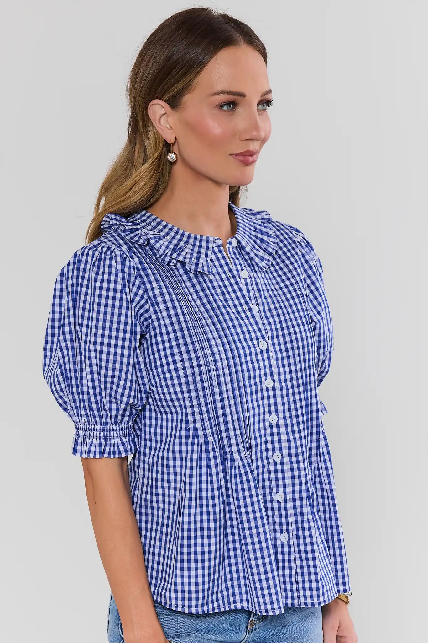 Woman side wearing a blue checkered blouse against a gray background