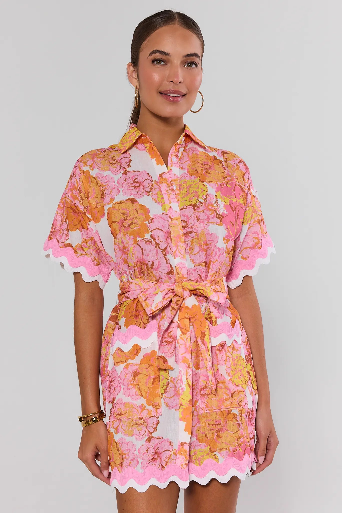Woman wearing a pink and orange floral dress on a white background standing