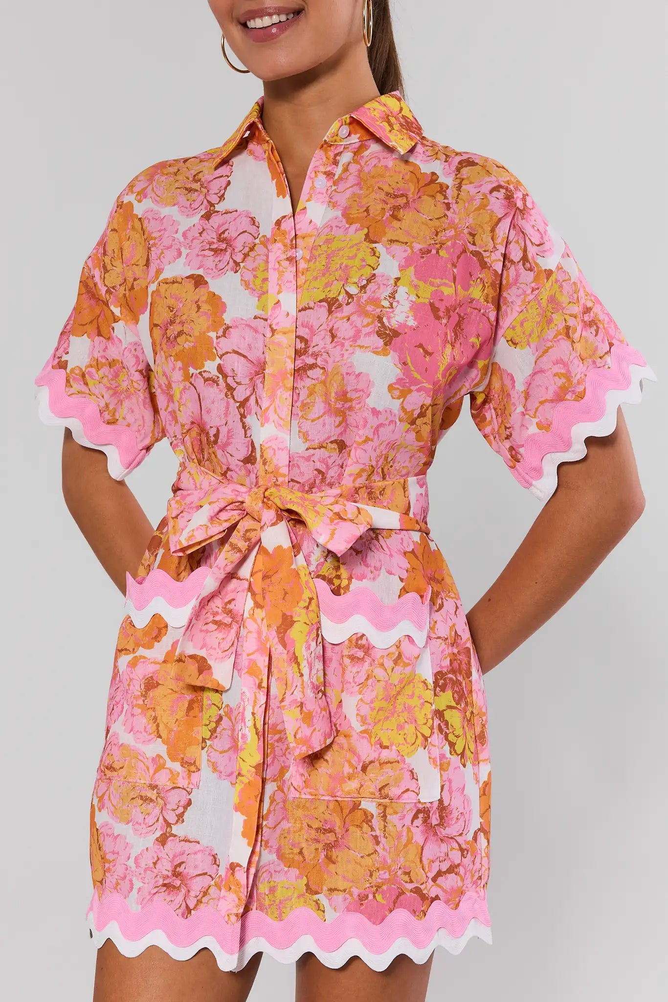 Woman wearing a pink and orange floral dress on a gray background close up